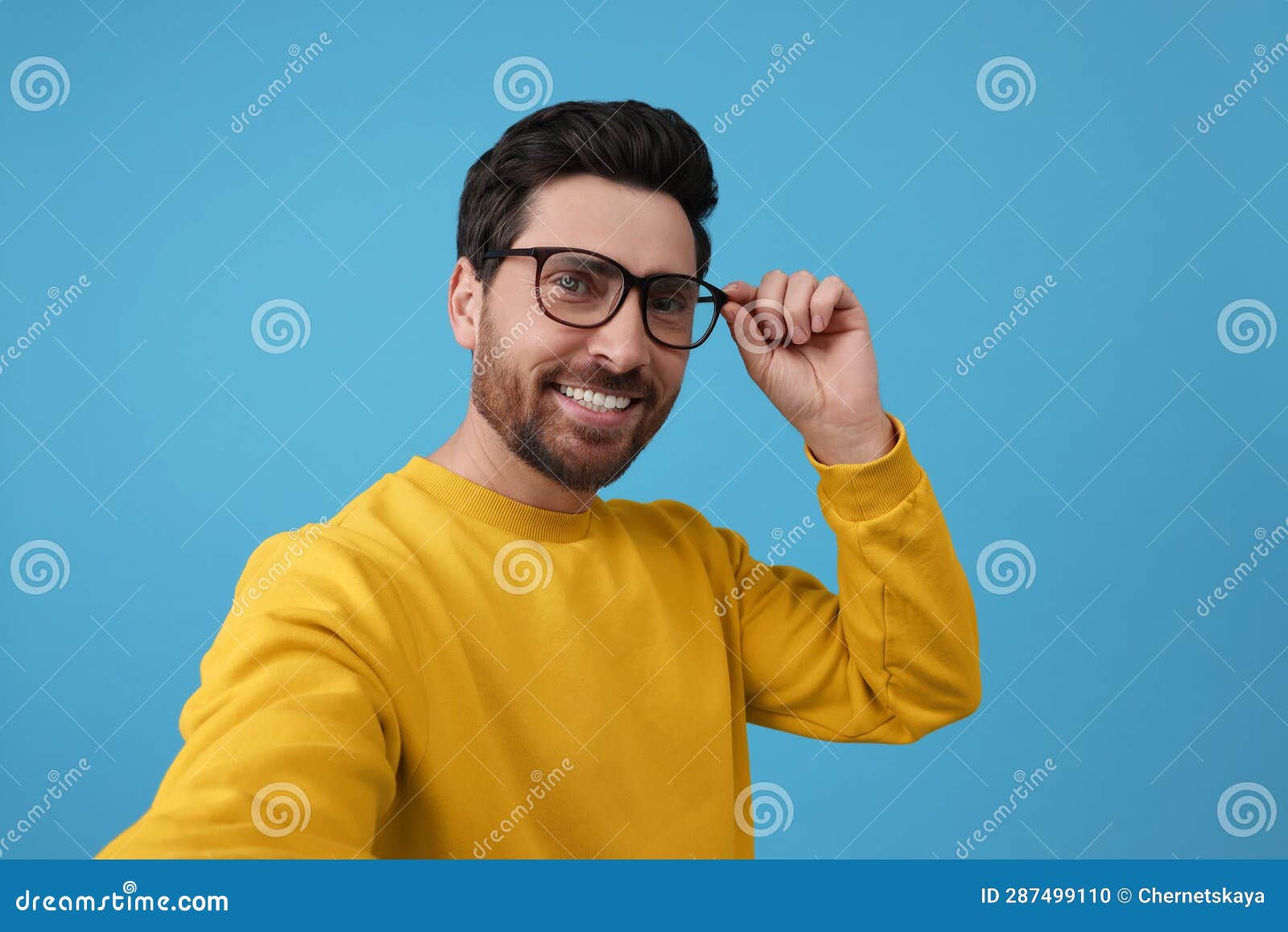 Smiling Man Taking Selfie on Light Blue Background Stock Photo Image