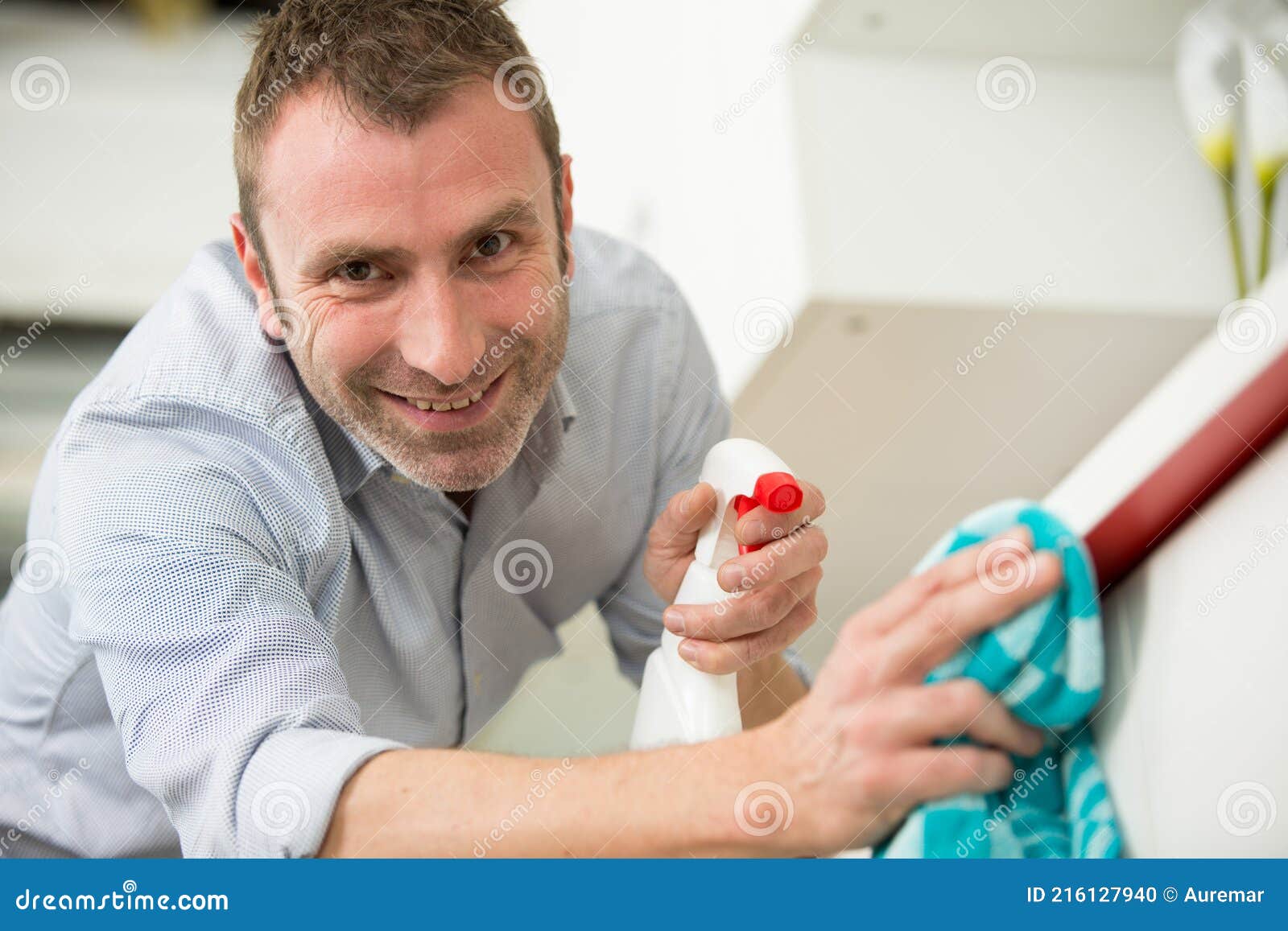 Smiling Man Using Cleaning Cloth and Detergent Spray Stock Photo