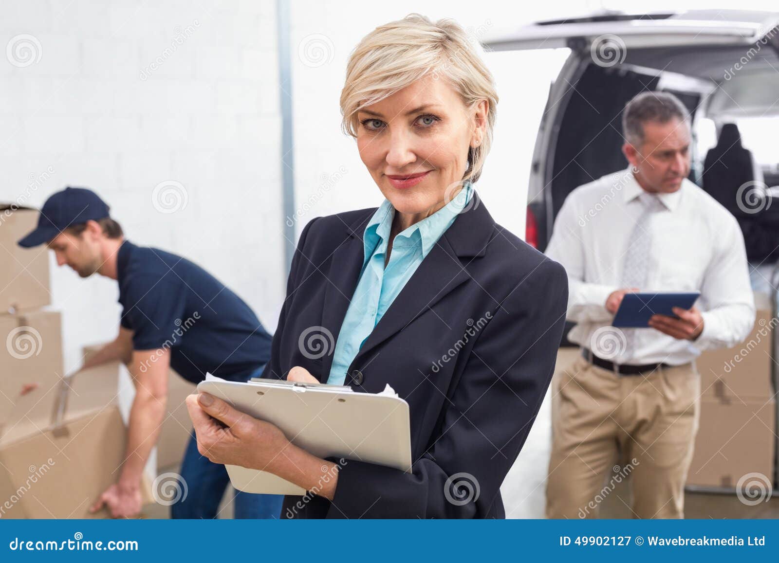 Smiling Manager Holding Clipboard in Front of His Colleagues Stock