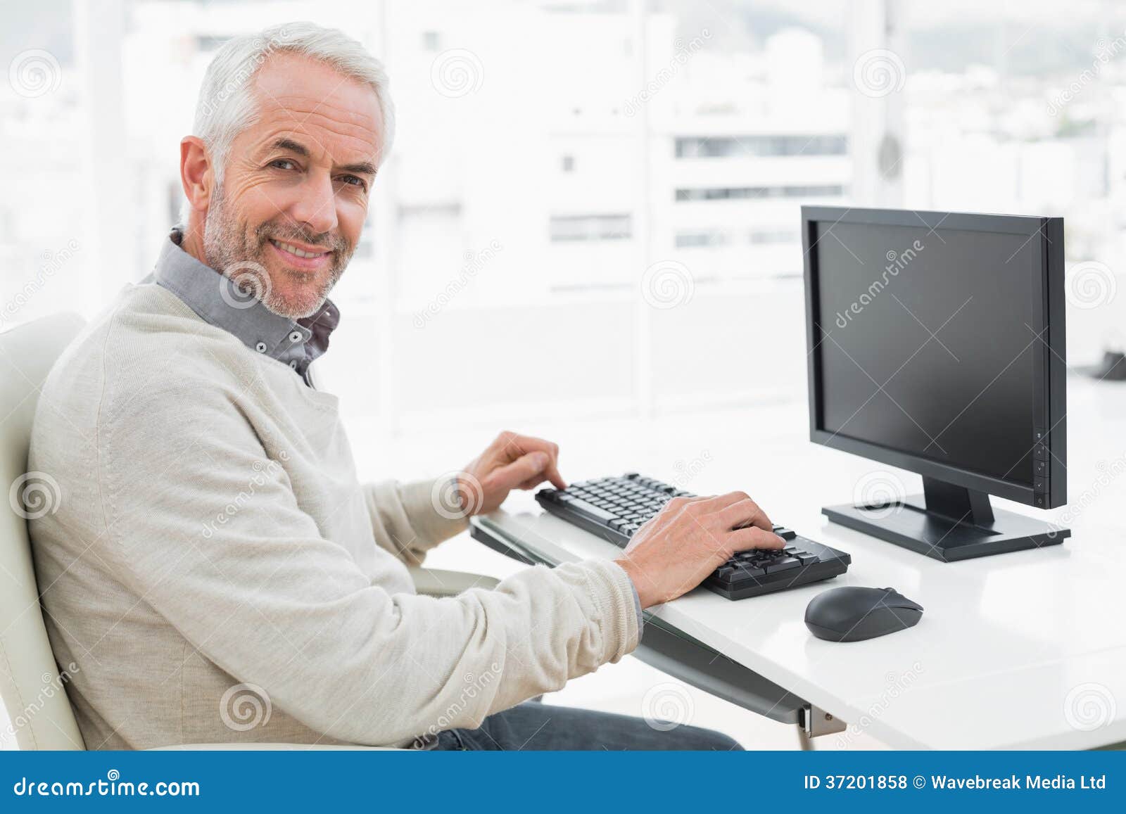 smiling mature man using computer at desk in office