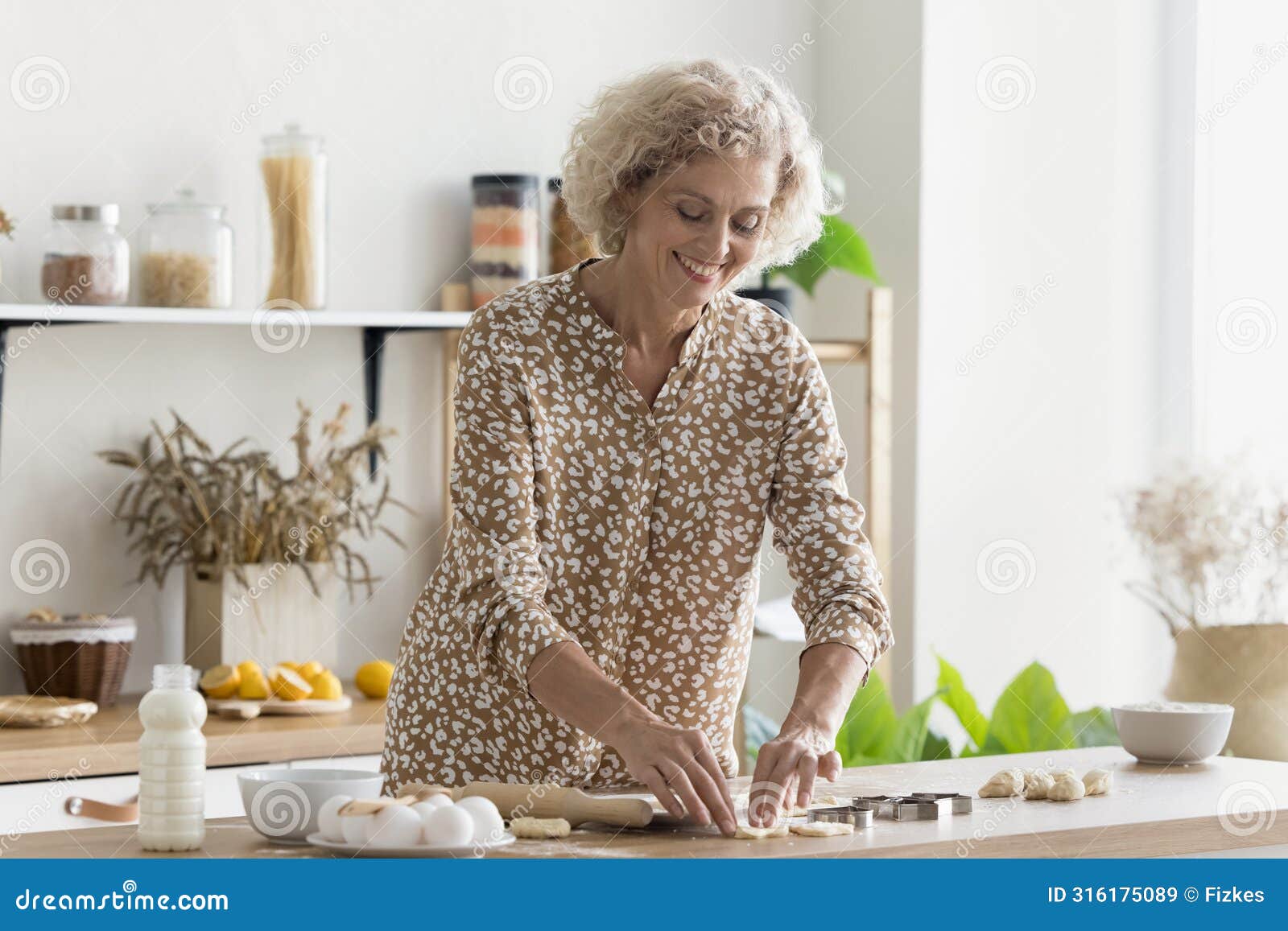 smiling mature woman prepare homemade dessert in the kitchen