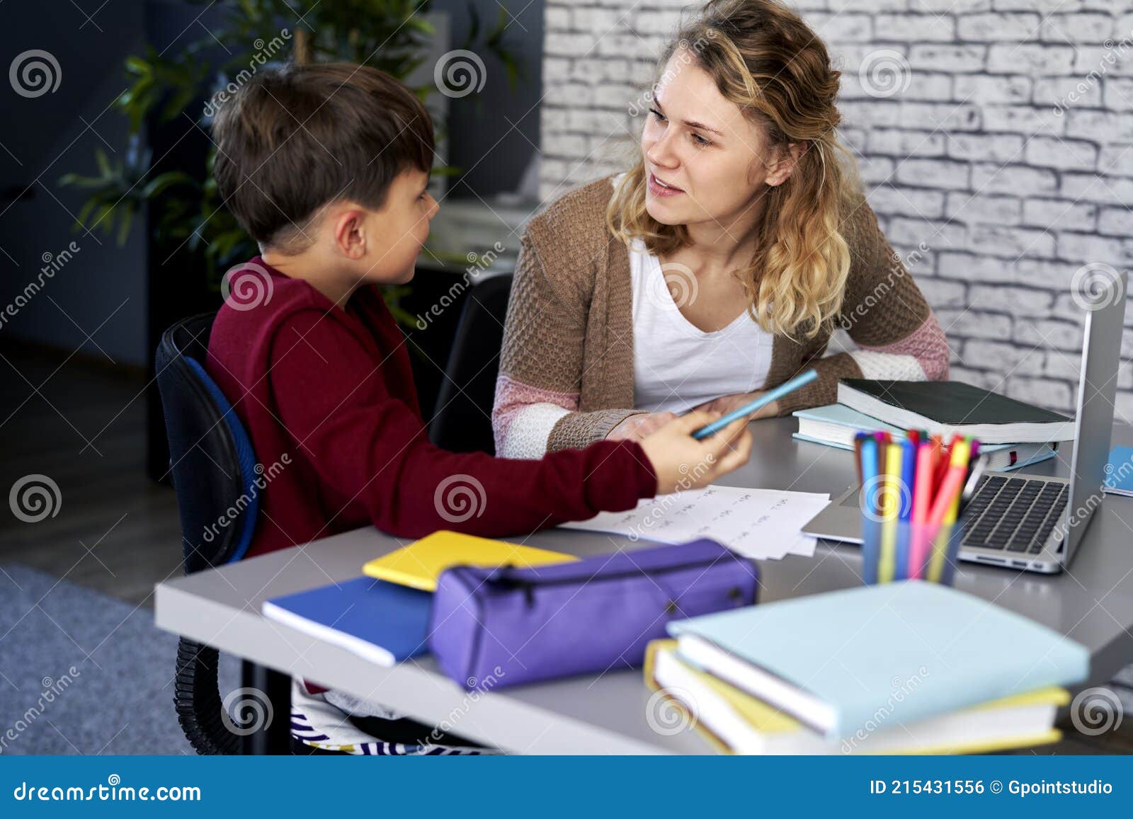 smiling mother explains to her son how to do the homework