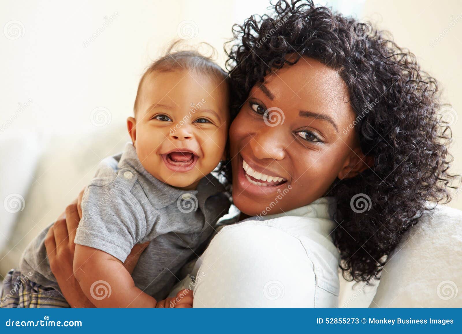 smiling mother playing with baby son at home