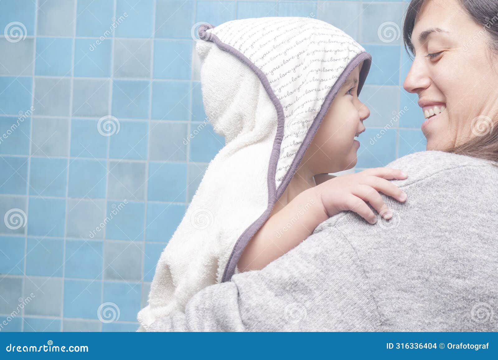 smiling mother and son look at each other with great complicity as the mother towels her son dry