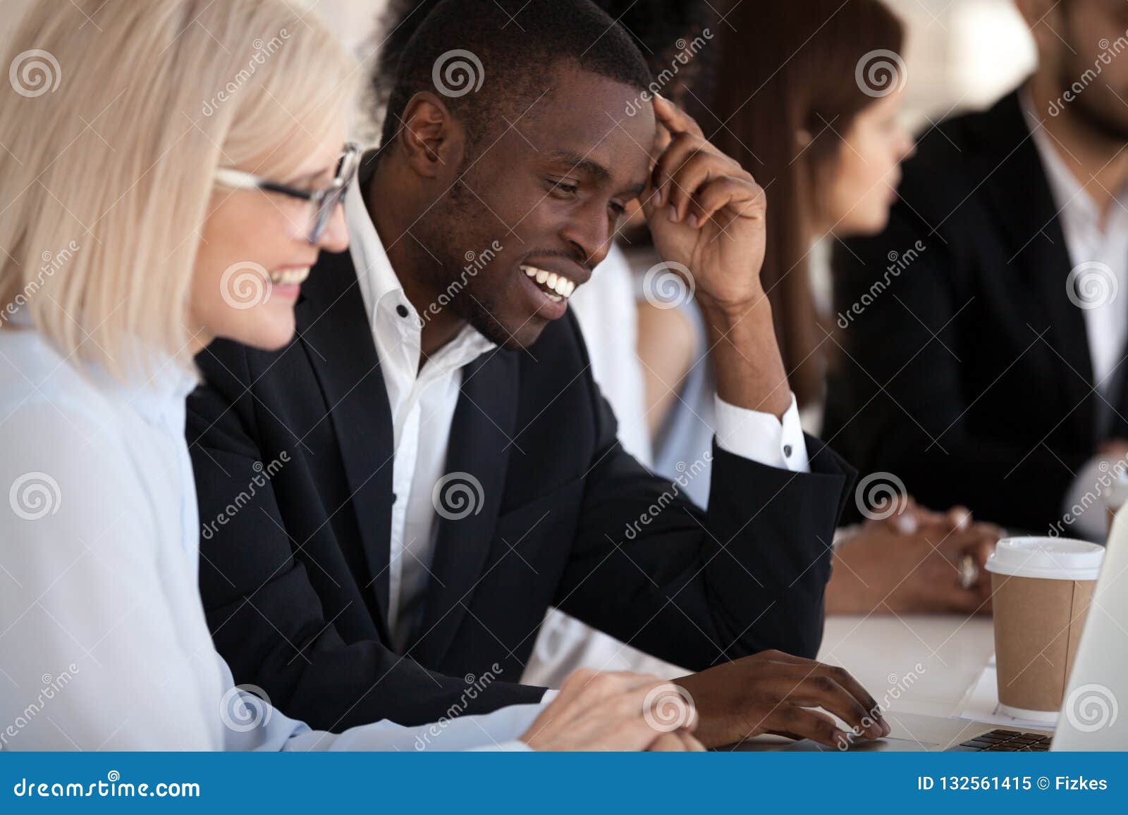 smiling multi-ethnic coworkers working together in office using