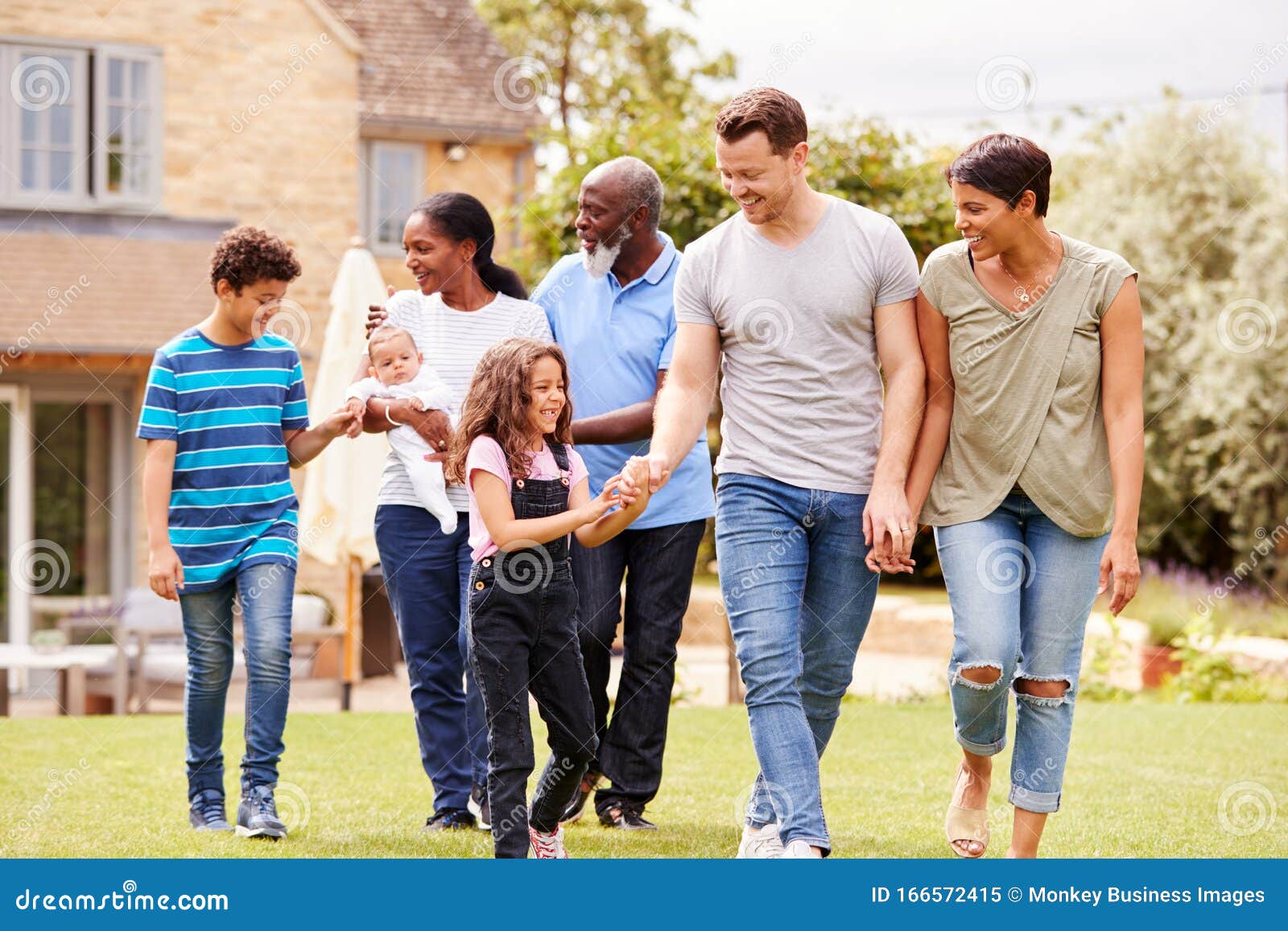 smiling multi-generation mixed race family in garden at home together