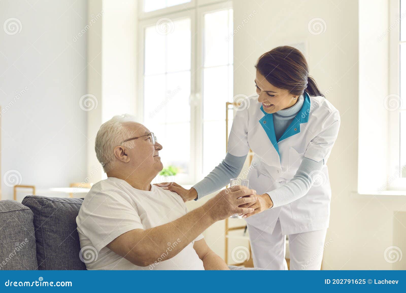 smiling nurse giving glass of water to senior man in nursing home or assisted living facility