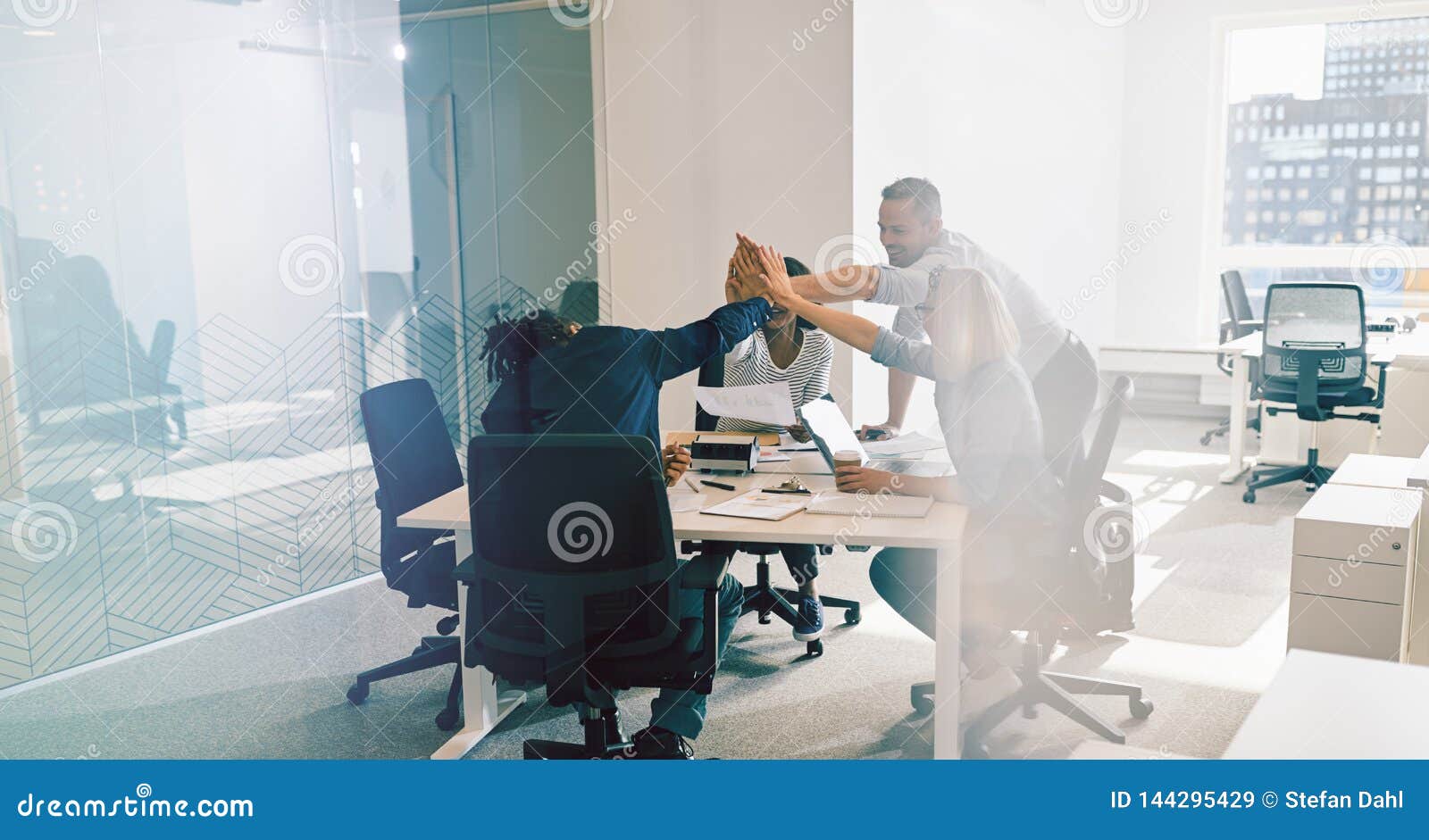 smiling office workers high fiving together during a meeting
