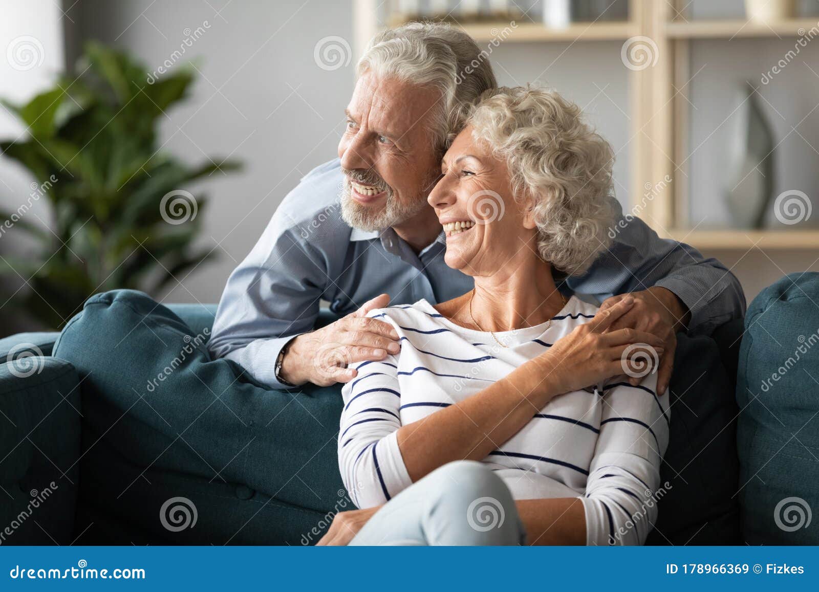 smiling older couple dreaming together, looking out window