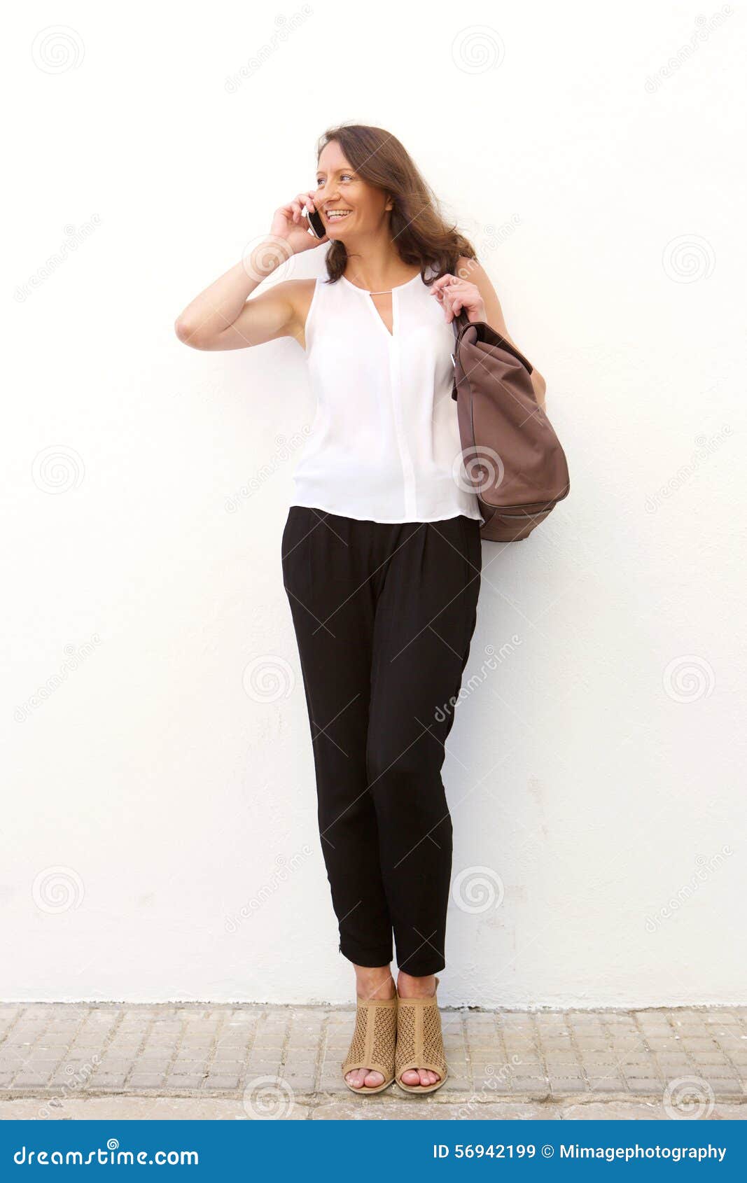 A Woman Carrying a Bag and Talking on the Phone · Free Stock Photo