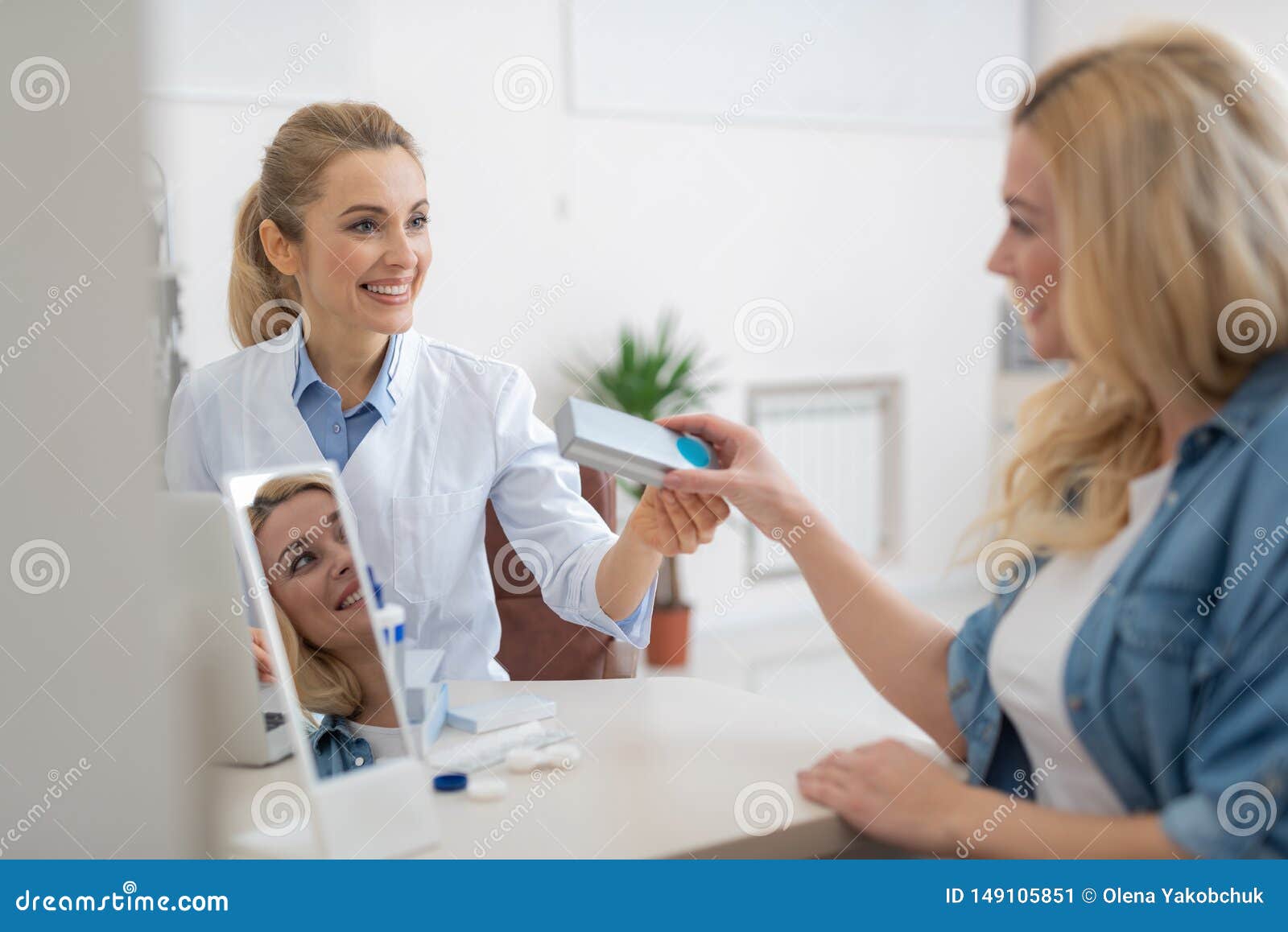 friendly ophthalmologist in white lab coat prescribing contact lenses for blond lady