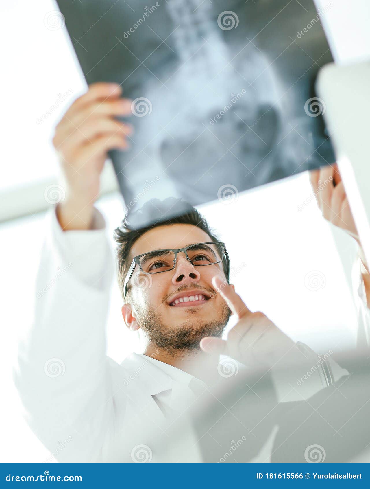 smiling orthopedist doctor looks at the x - ray of the patient