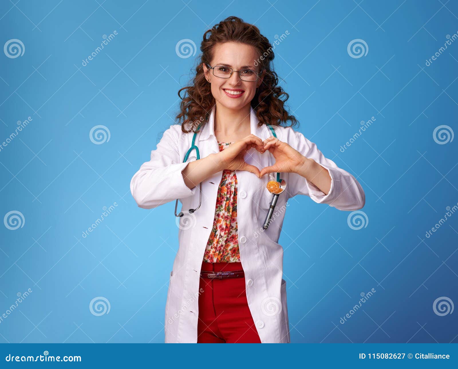 smiling pediatrist doctor showing heart d hands on blue