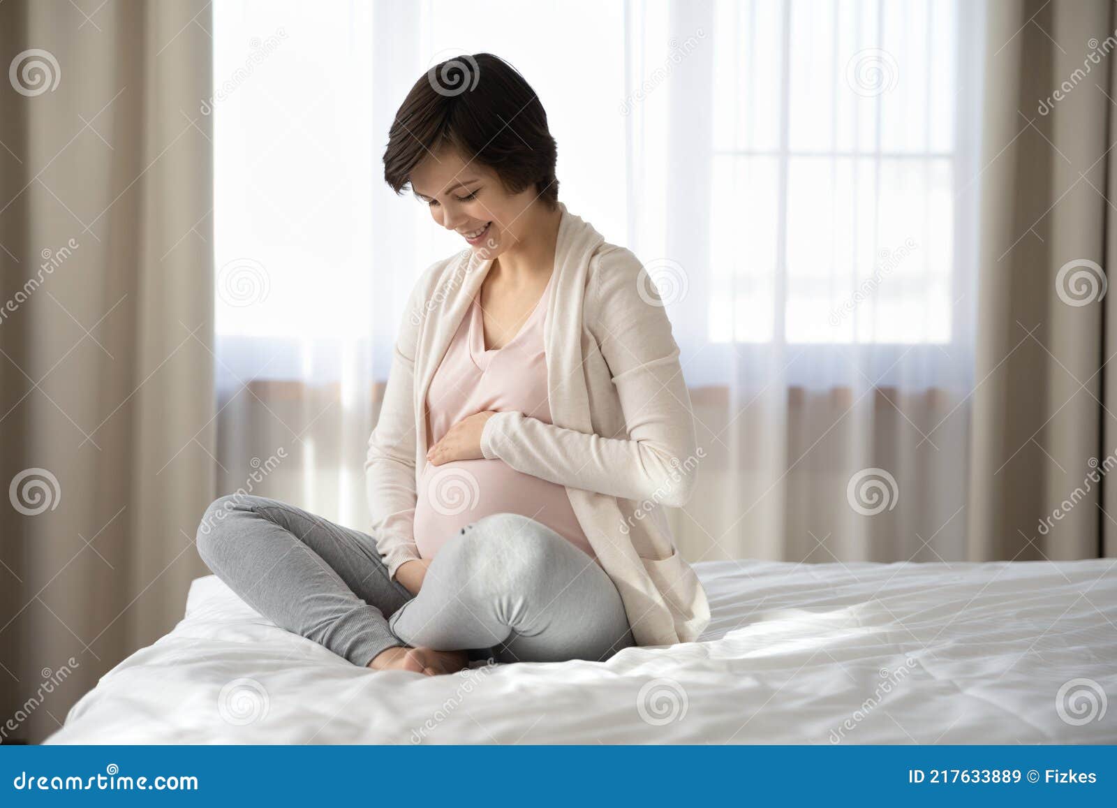 smiling pregnant woman caress baby bump relaxing