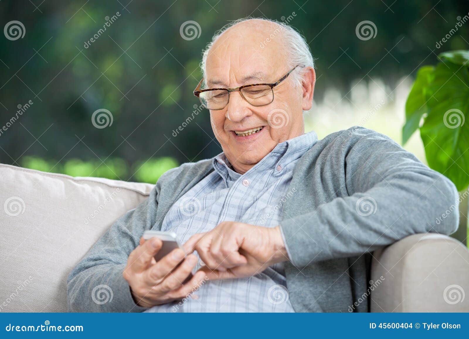 Smiling senior man text messaging through mobile phone at nursing home porch