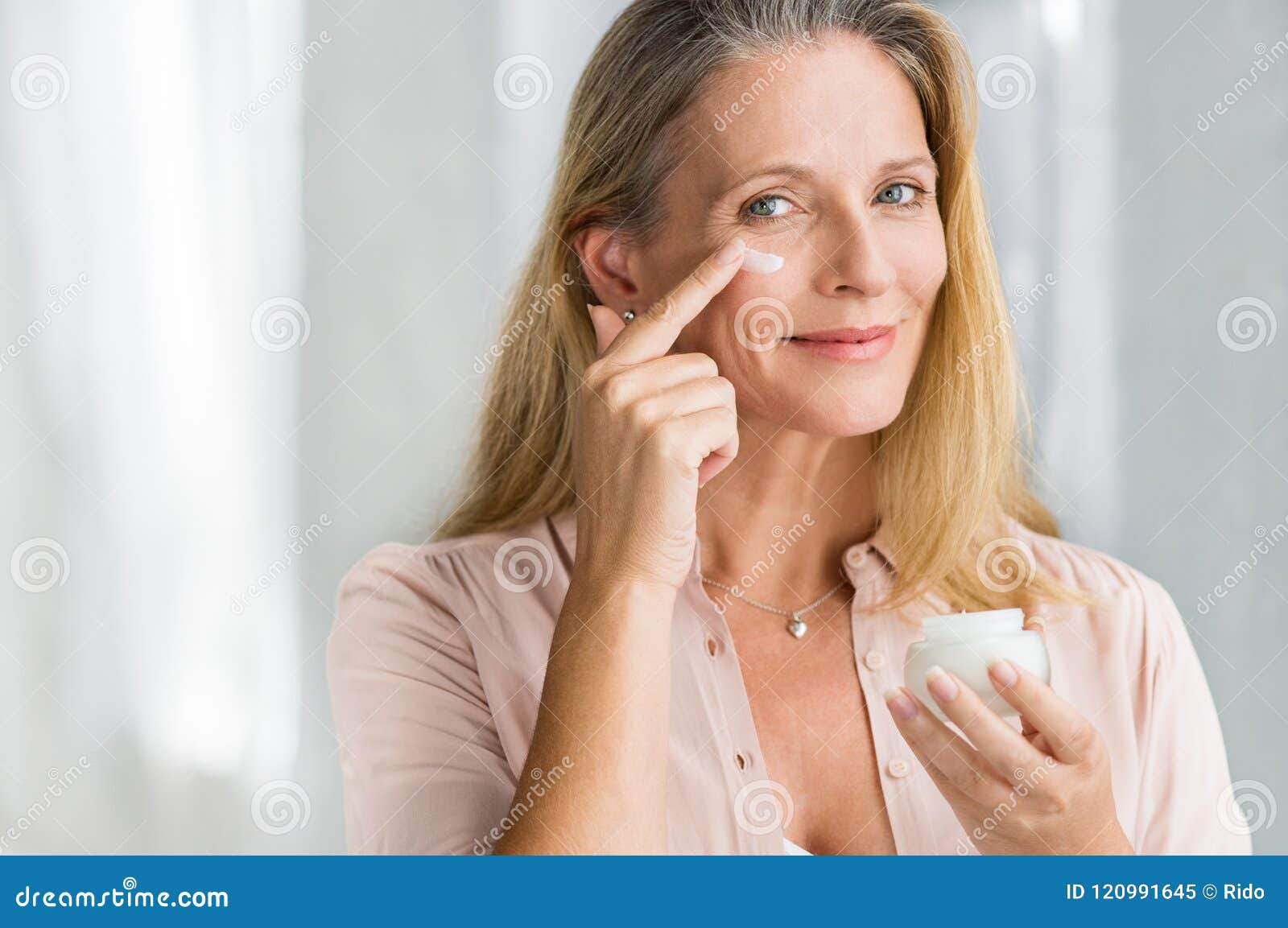 woman applying anti aging lotion on face