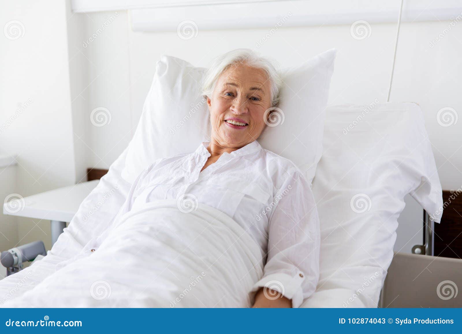 Smiling Senior Woman Lying On Bed At Hospital Ward Stock