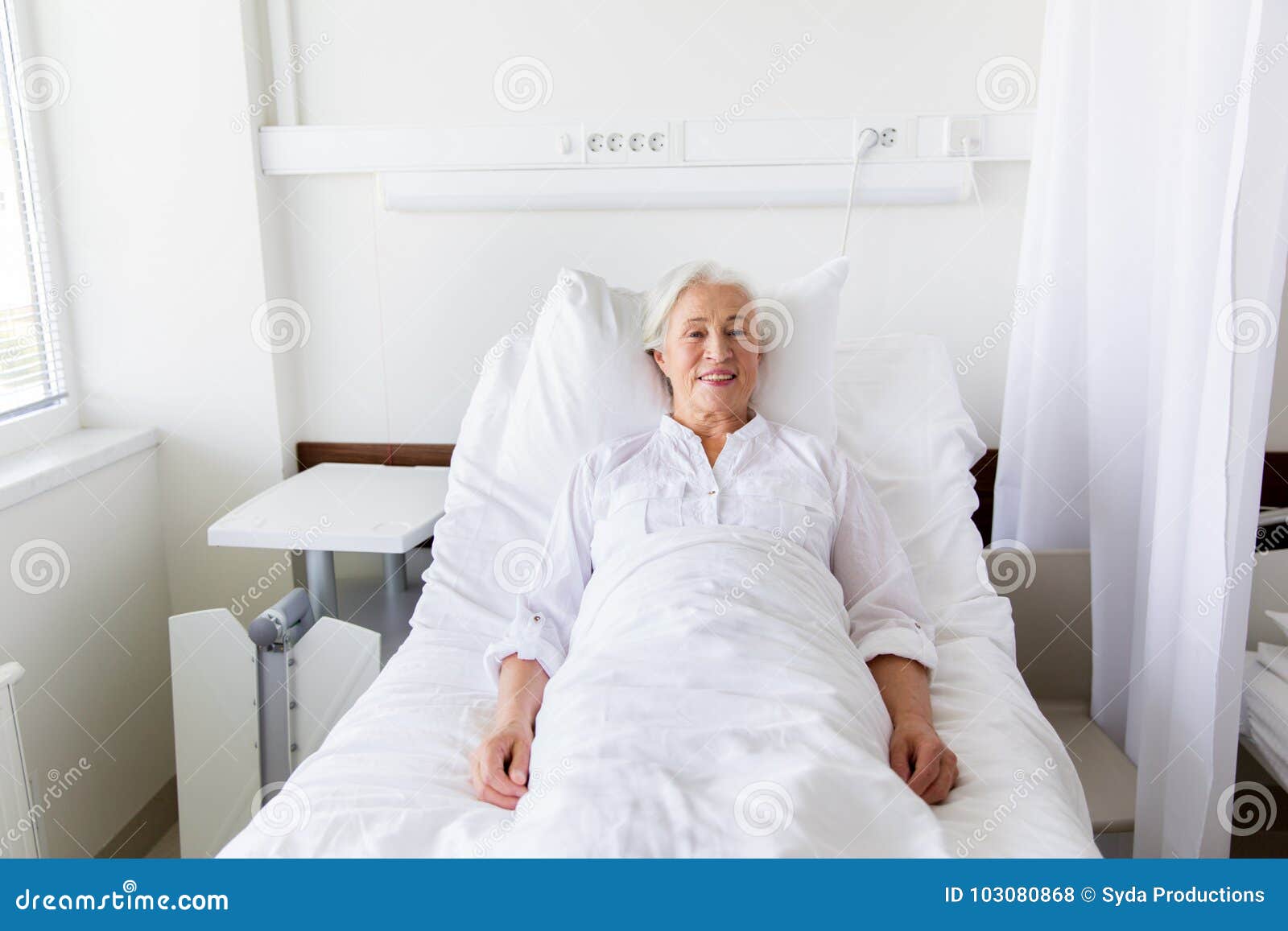 Smiling Senior Woman Lying On Bed At Hospital Ward Stock