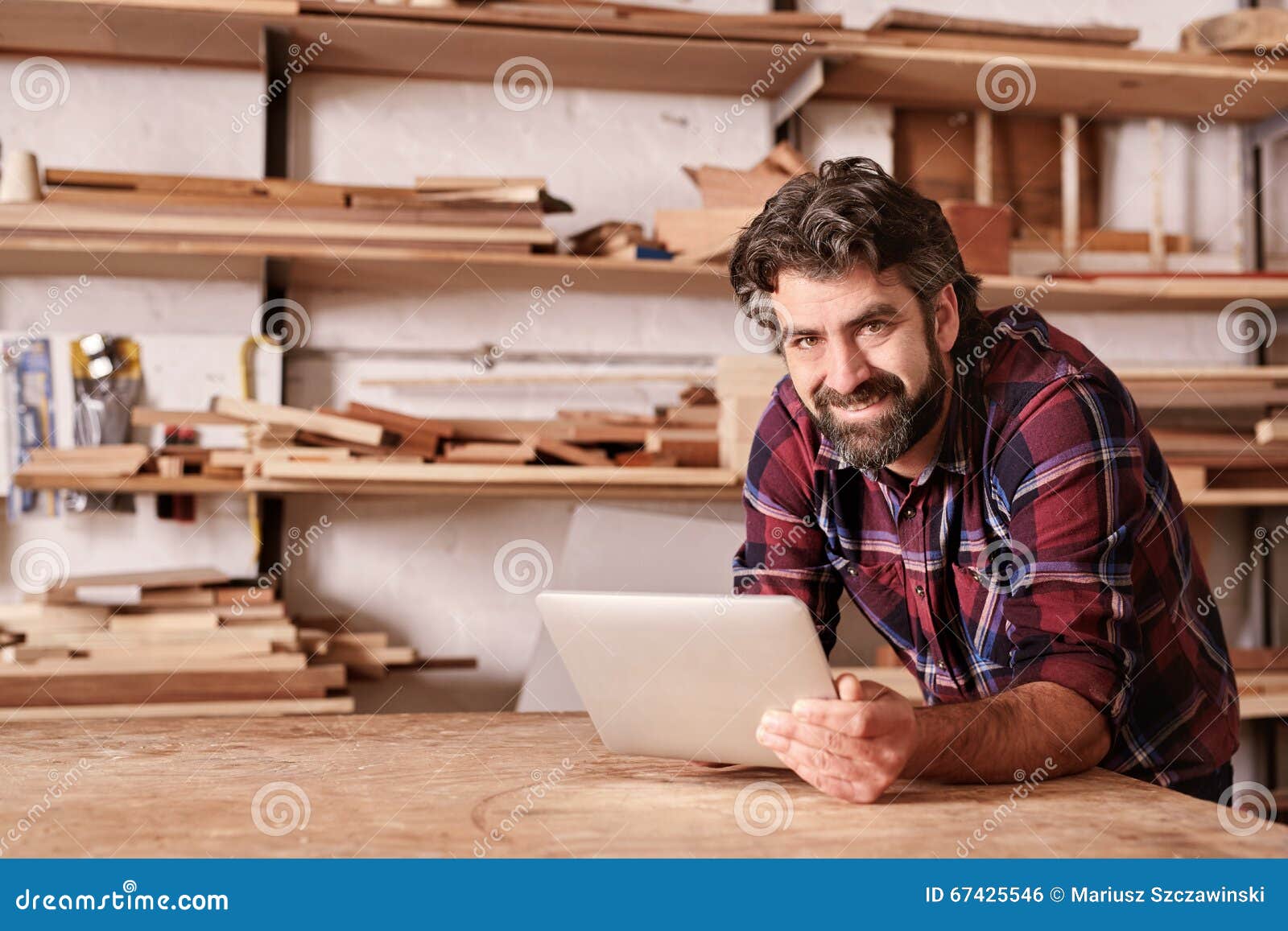 smiling small business owner in woodwork studio with digital tab