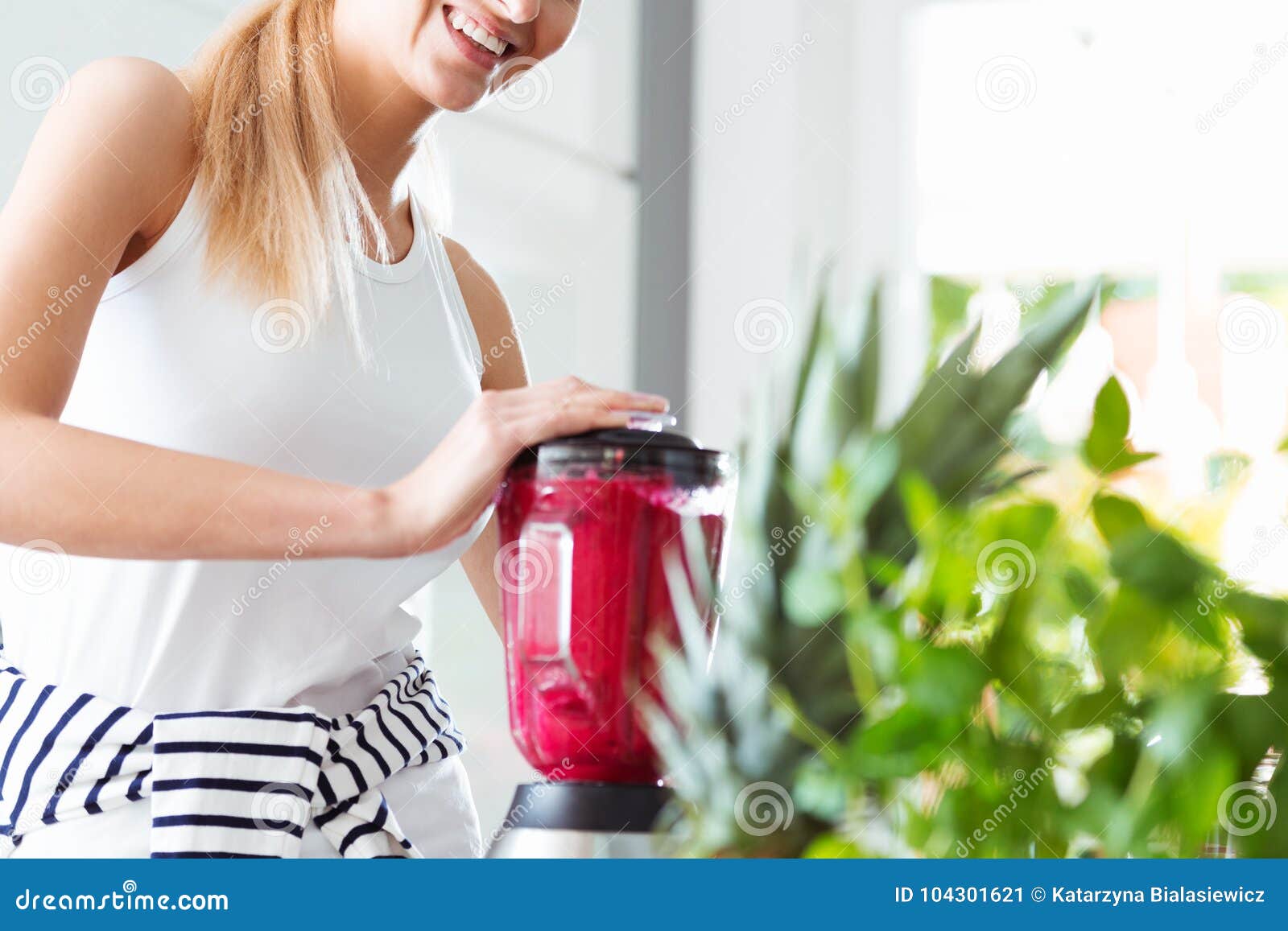 smiling woman blending red smoothie