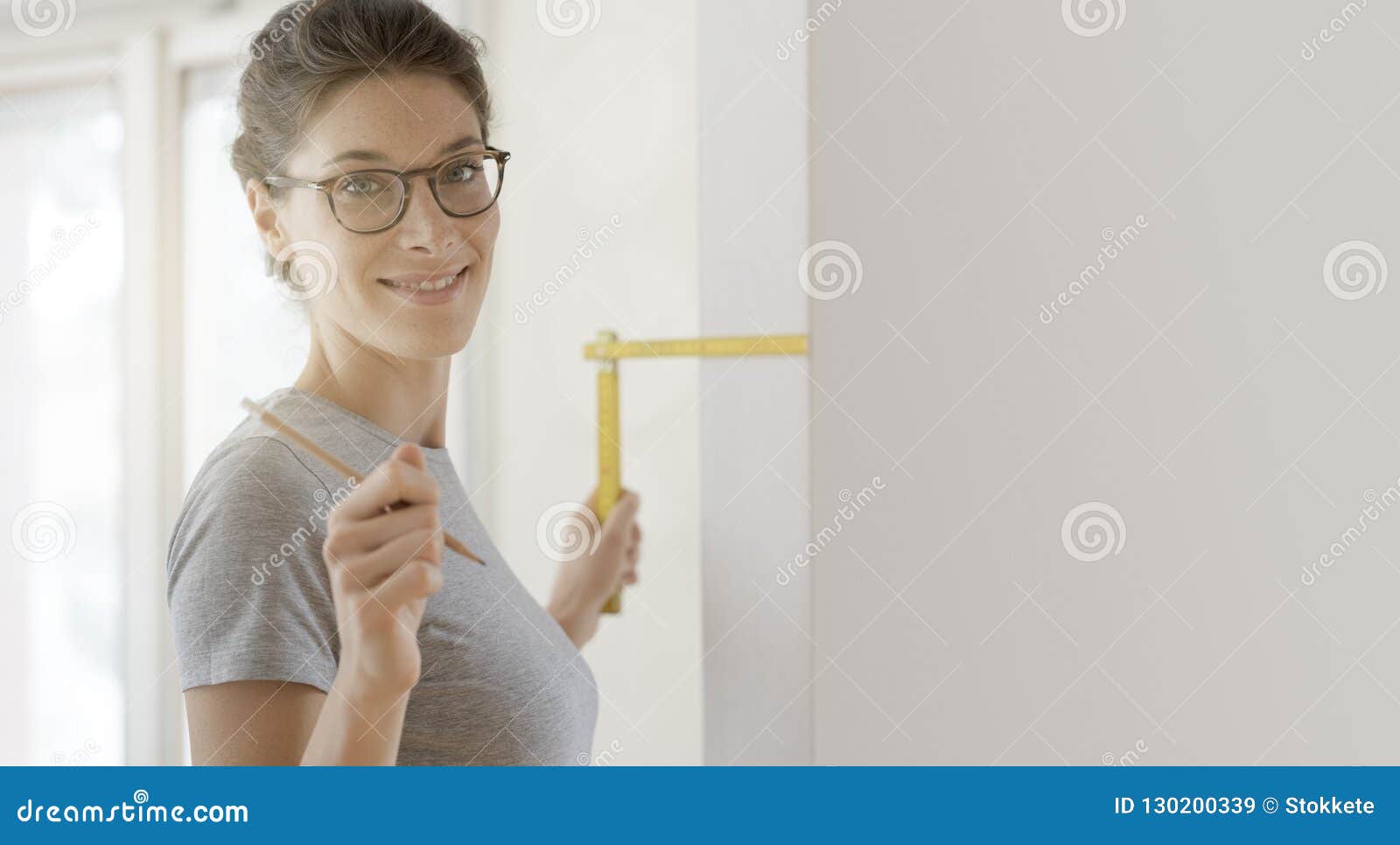 smiling woman doing a home makeover and measuring with a ruler