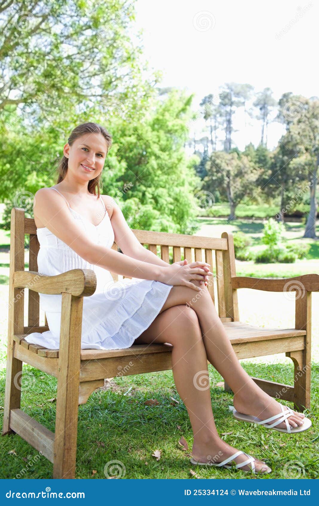 Smiling Woman With Her Legs Crossed Sitting On A Park Bench Stock Photo ...