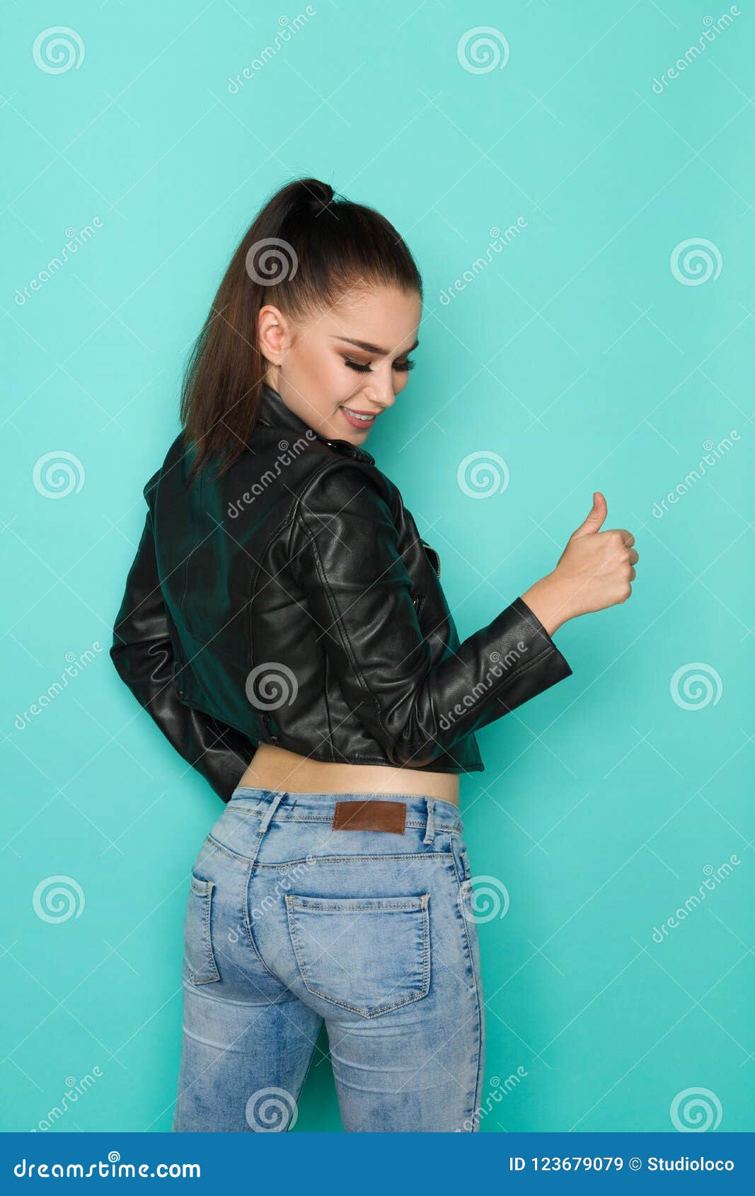 Smiling Woman in Leather Jacket is Looking Over Shoulder and Showing ...
