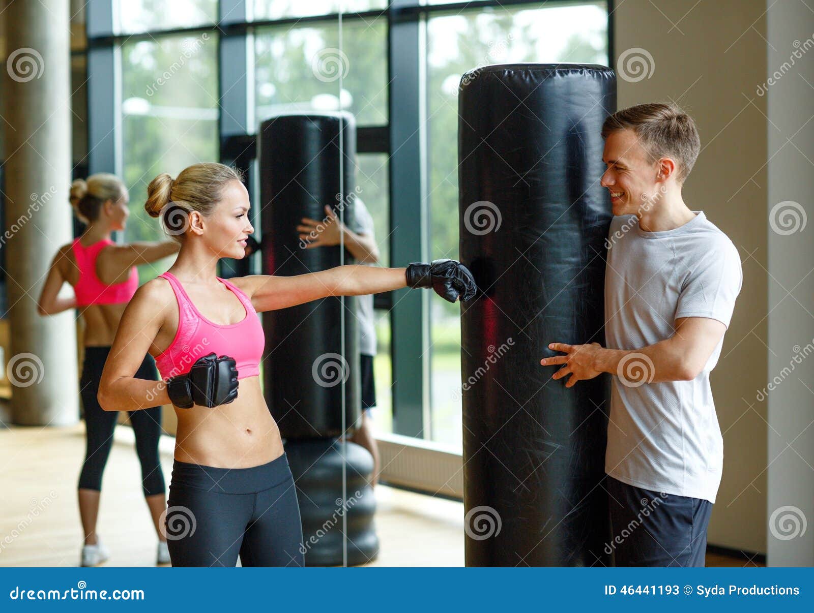 Smiling Woman With Personal Trainer Boxing In Gym Stock