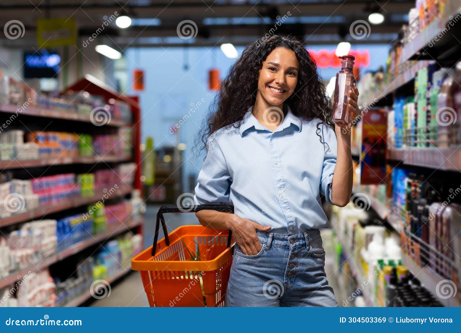 Smiling Woman Shopping in Supermarket Aisle Holding Bottle and Basket ...