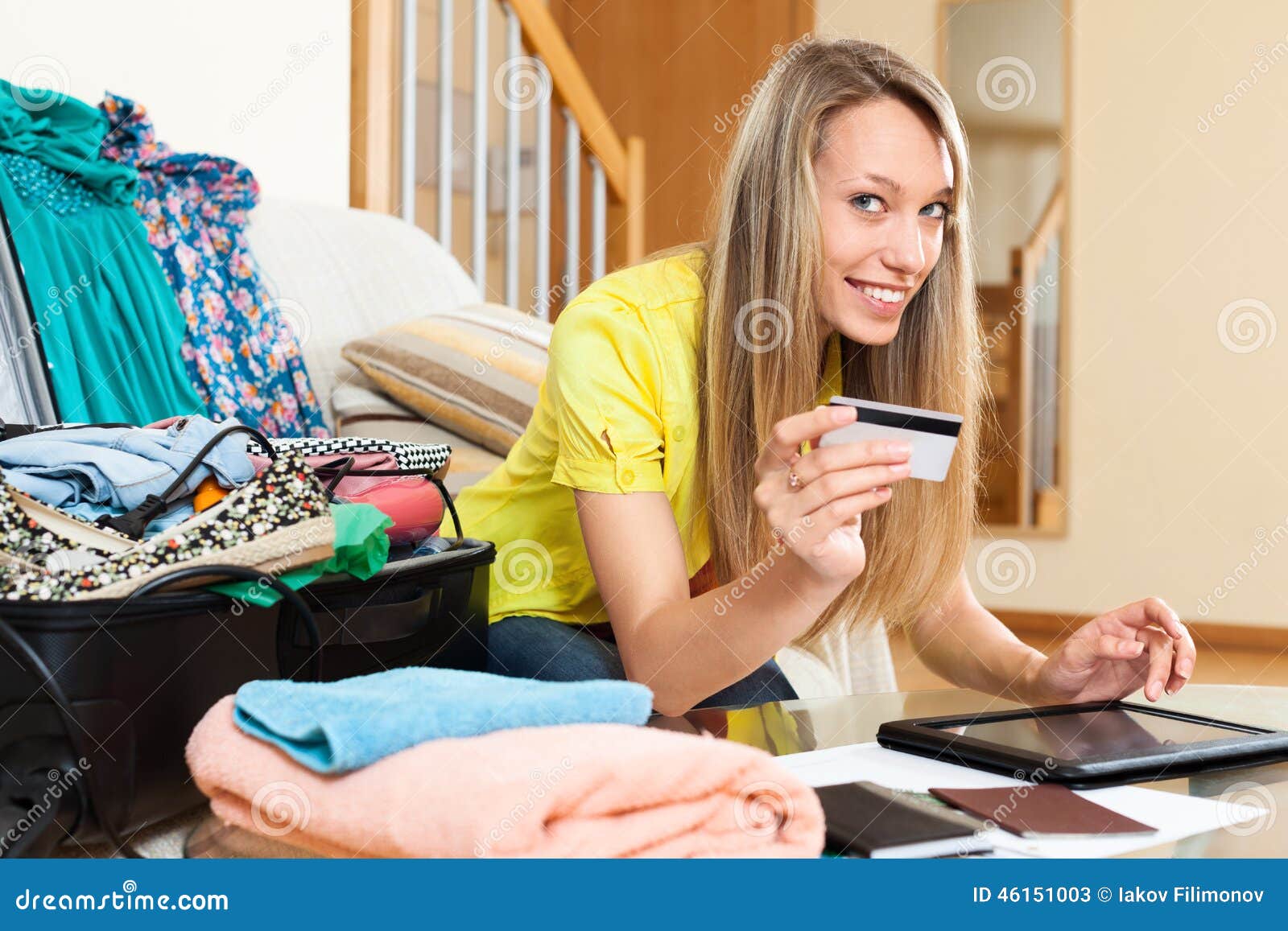 Smiling woman using credit card for reserving plane ticket. Smiling woman using credit card and tablet for reserving plane ticket