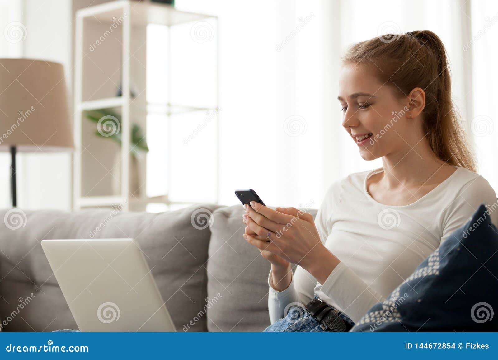 Smiling Woman Using Phone, Mobile Device App, Sitting on Sofa Stock ...