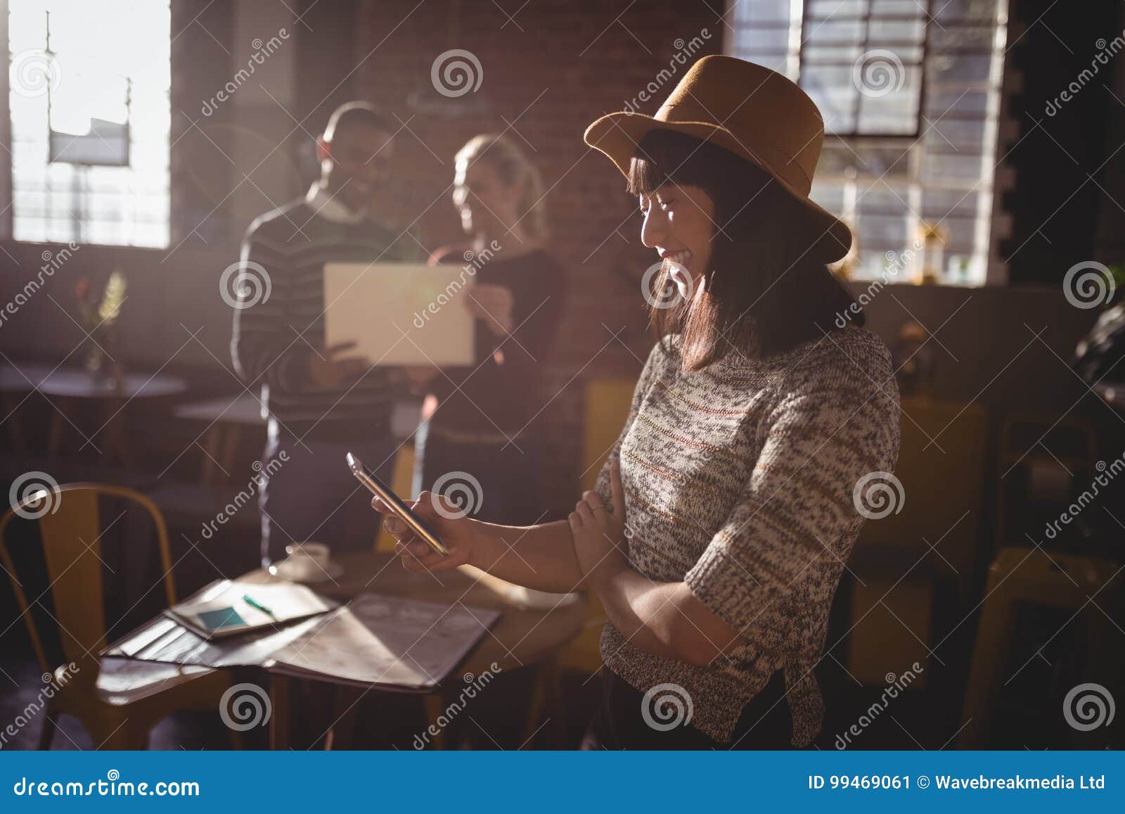 smiling woman using smartphone against colleauges
