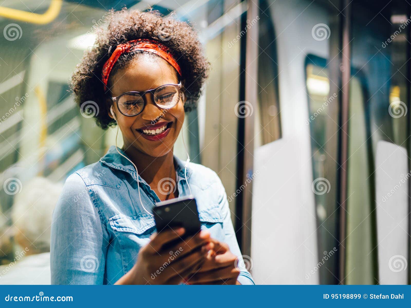 smiling young african woman listening to music on her commute