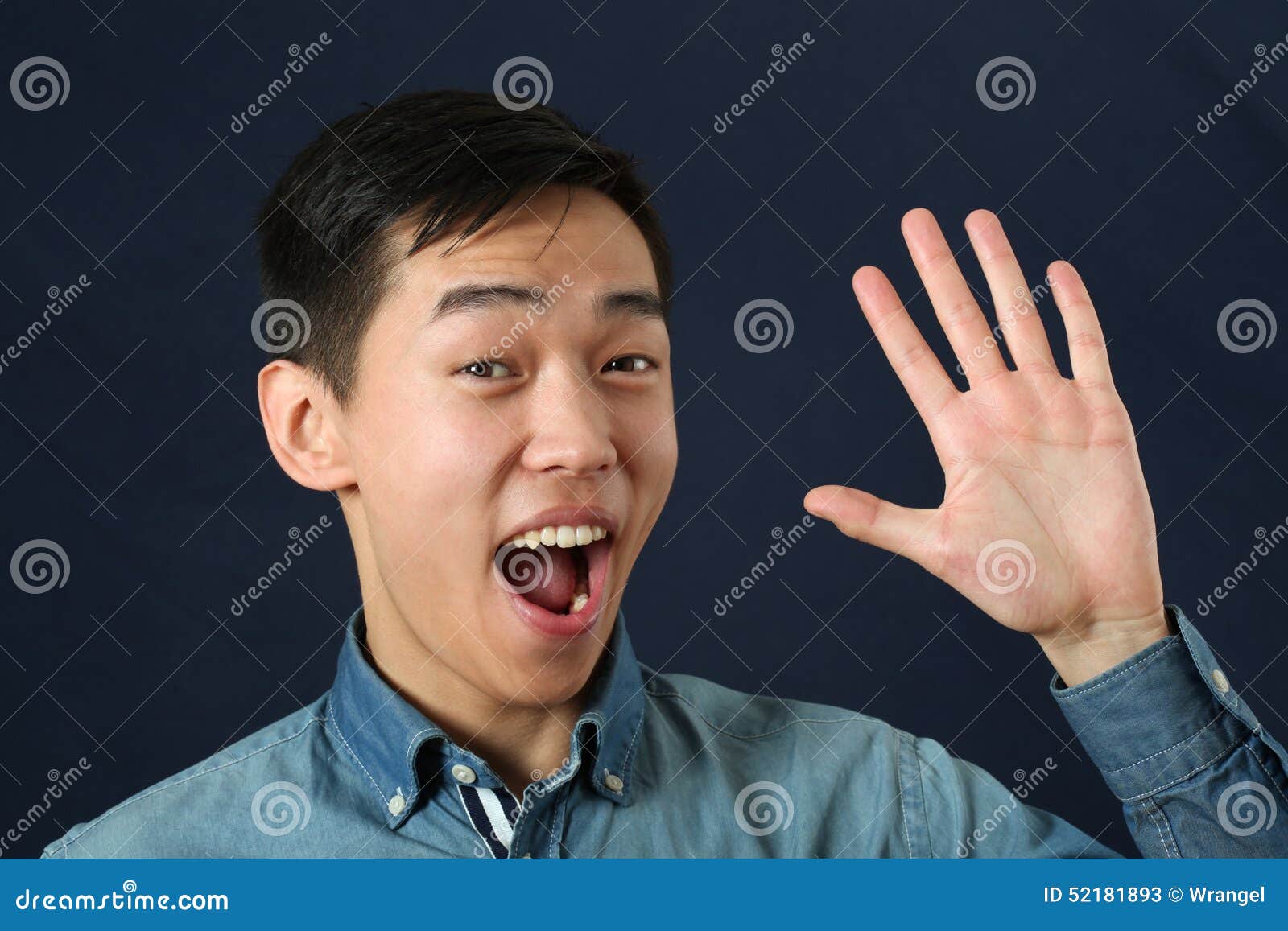 Smiling Young Asian Man Waving His Palm and Looking at Camera Stock