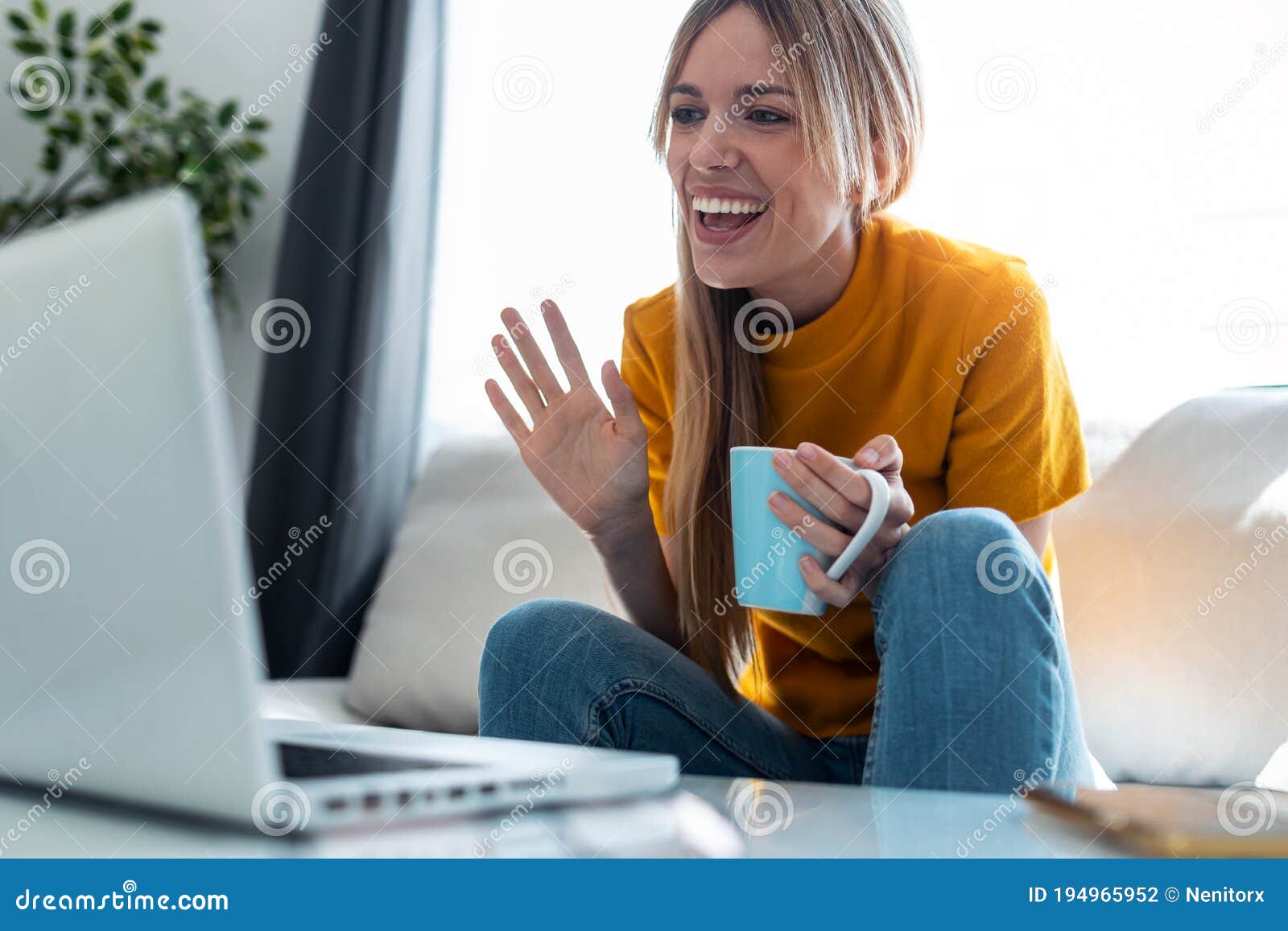 smiling young blonde woman having videocall on laptop sitting on the couch