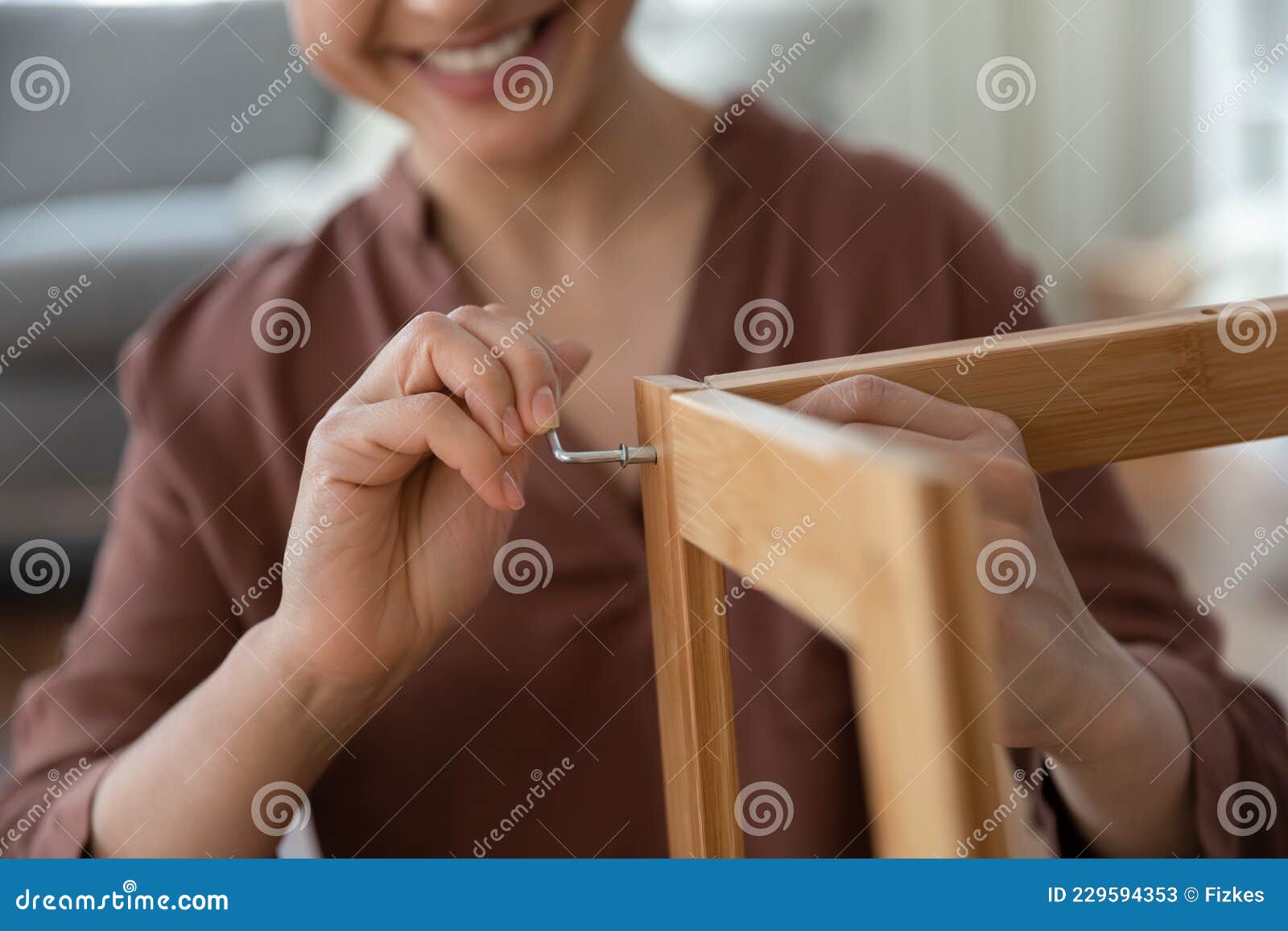 smiling young female assembling flat pack furniture using hex key