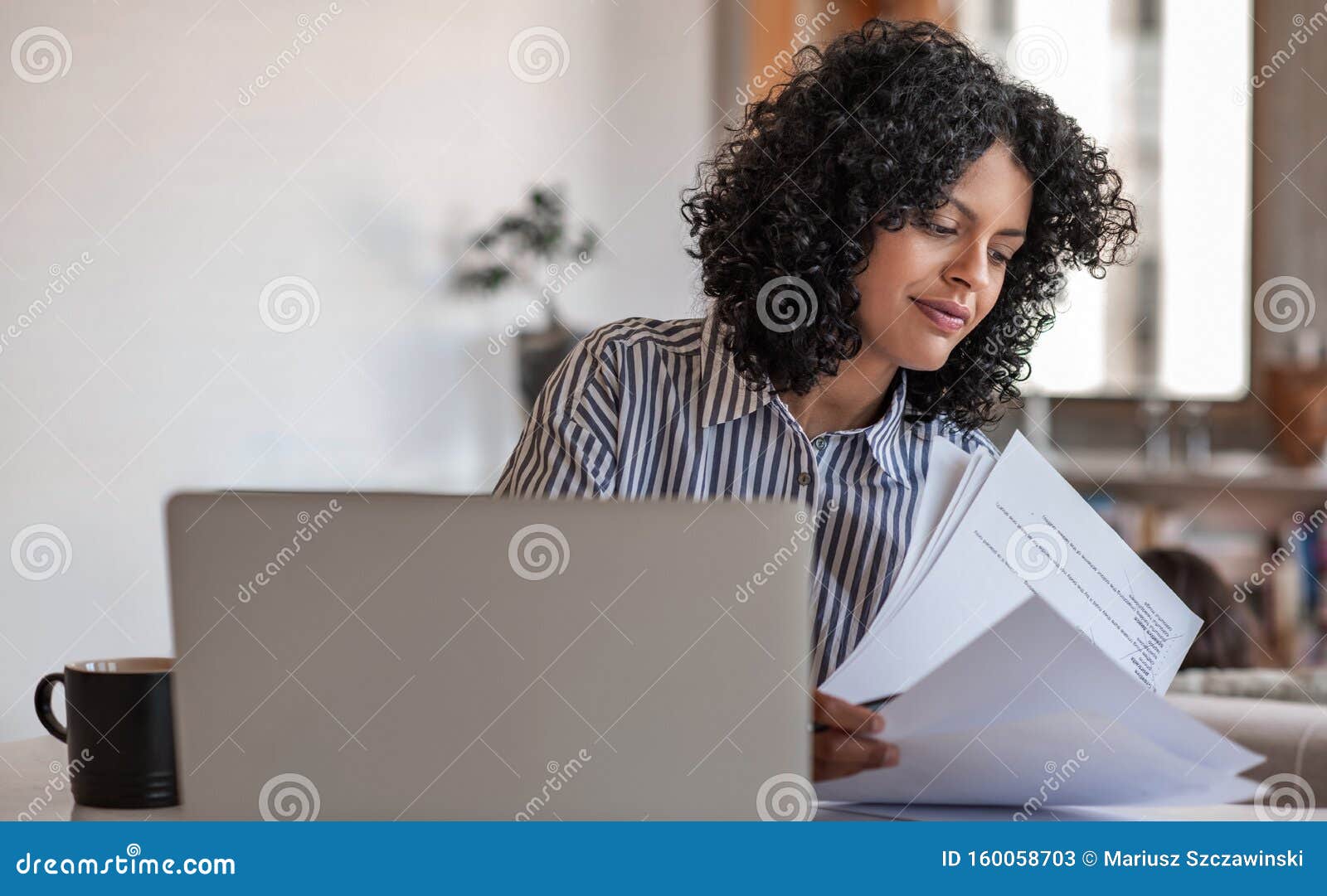 smiling young female entrepreneur going over paperwork at home