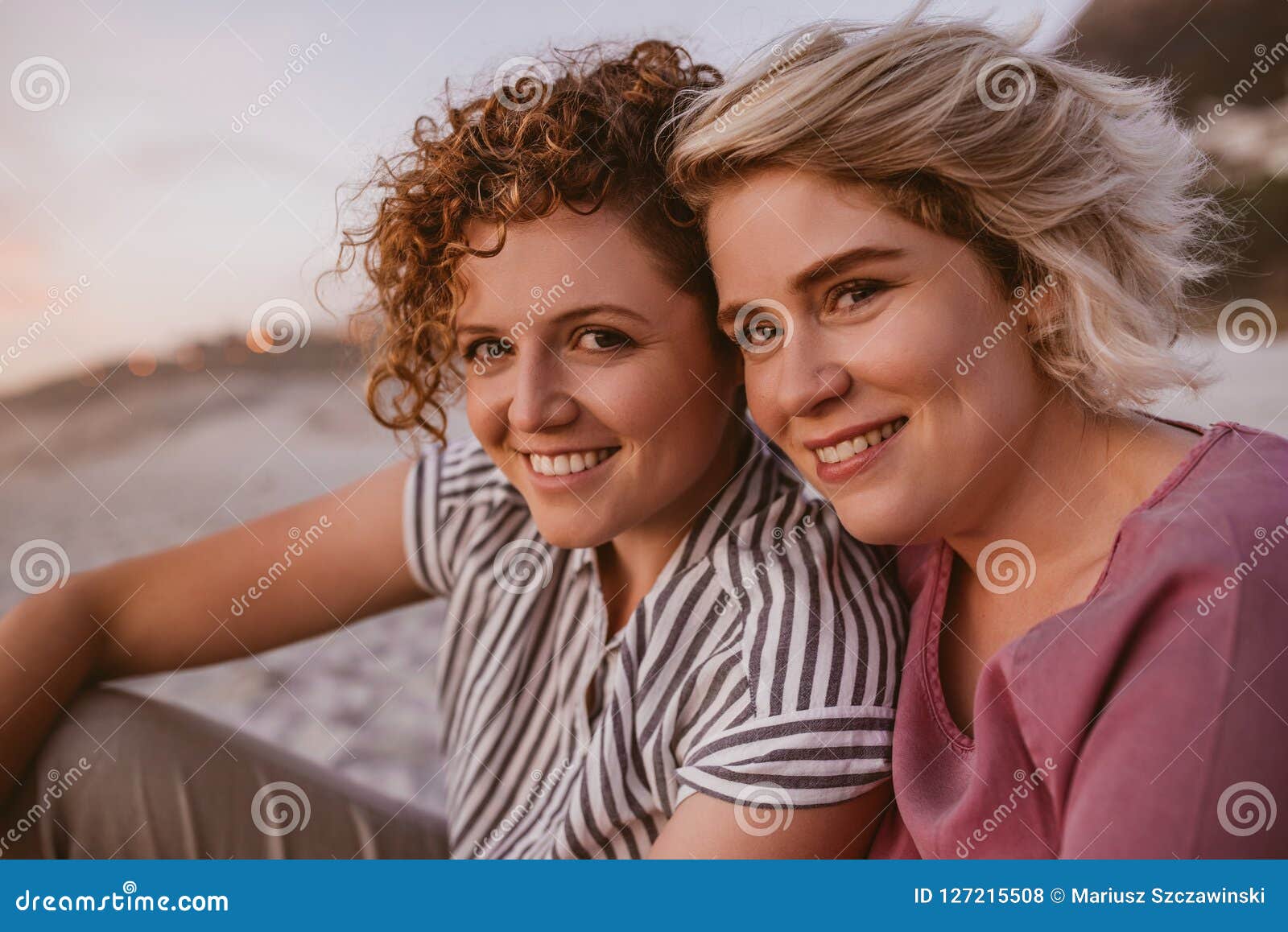 Smiling Young Lesbian Couple Enjoying A Romantic Beach Sunset Together