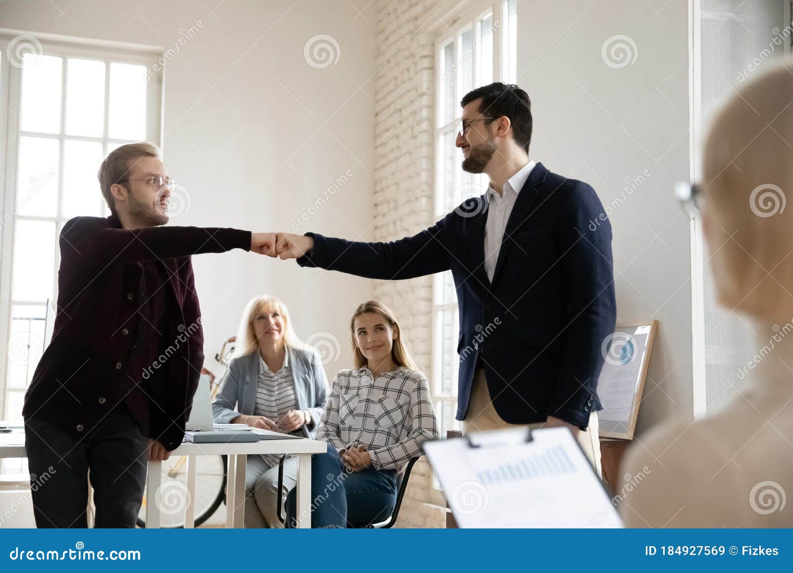 Smiling Young Male Employee Bumping Fists With Colleague In Office Stock Image Image Of 