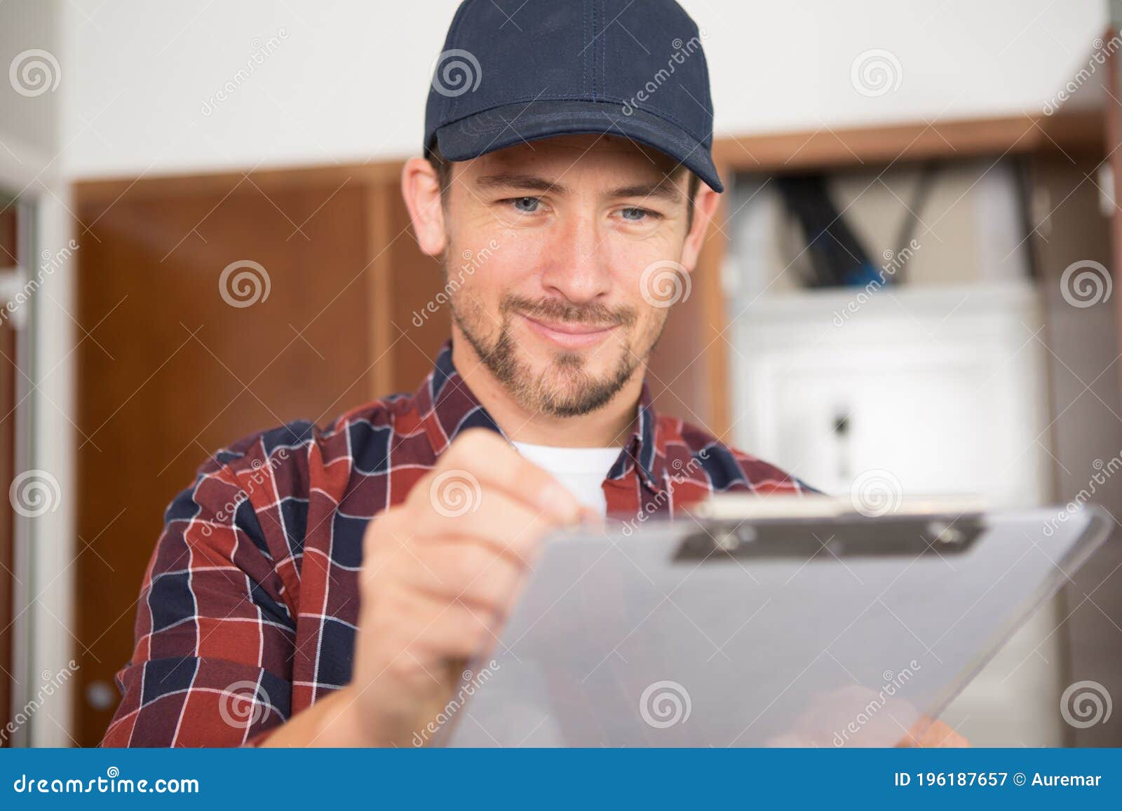 Smiling Young Man Writing on Clipboard Stock Image Image of indoors