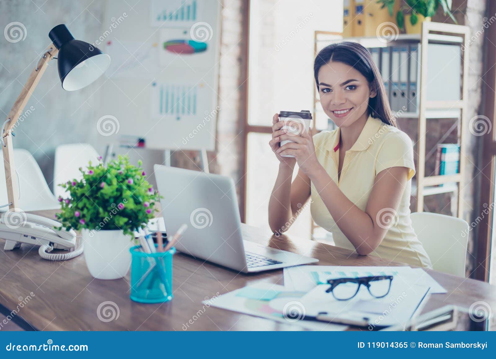smiling young mulatto girl is drinking coffee at the break in of