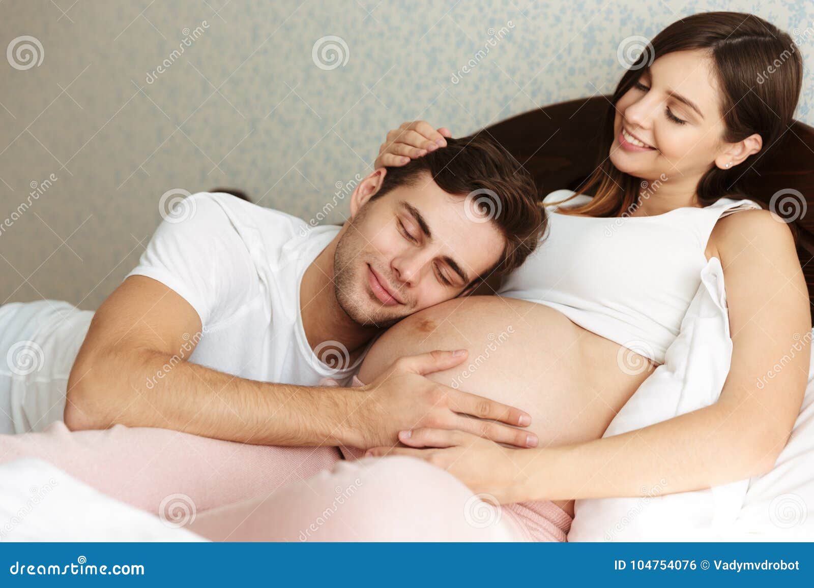 Smiling Young Pregnant Wife Lying in Bed with Her Husband Stock Photo picture