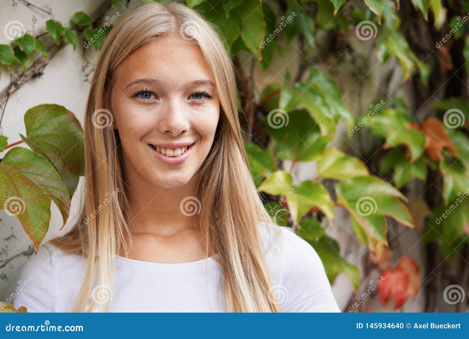 smiling young woman against ivy-clad wall