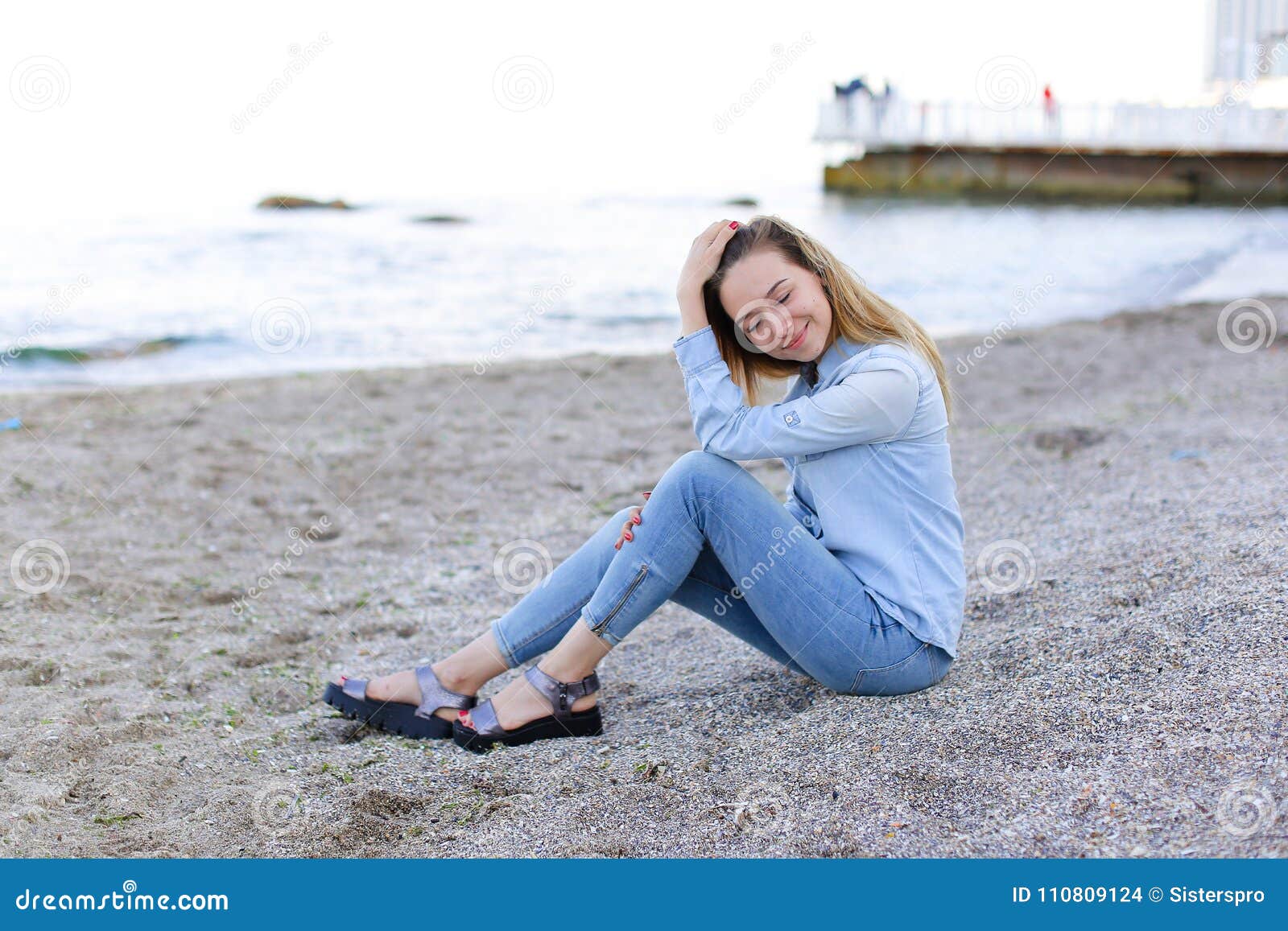 Smiling Young Woman Rests On Beach And Poses In Camera Sitting
