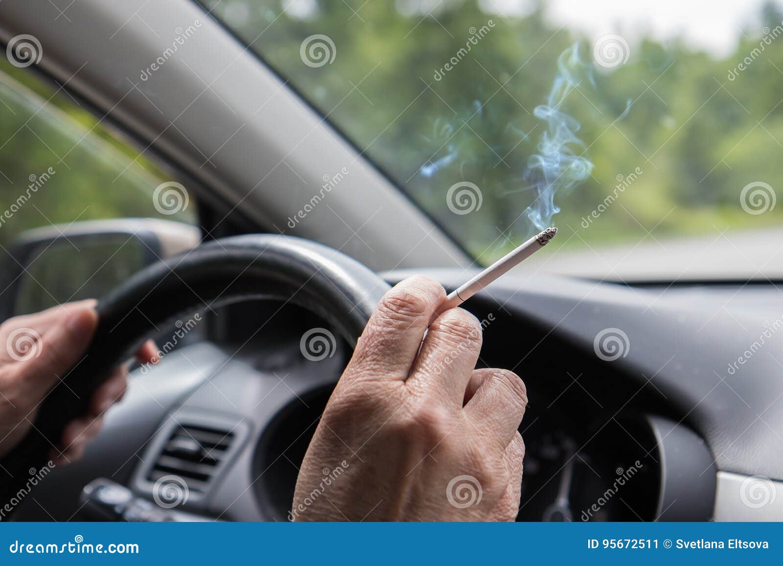 Smoking Cigarette in the Hand of Woman at Steering Wheel Stock Image