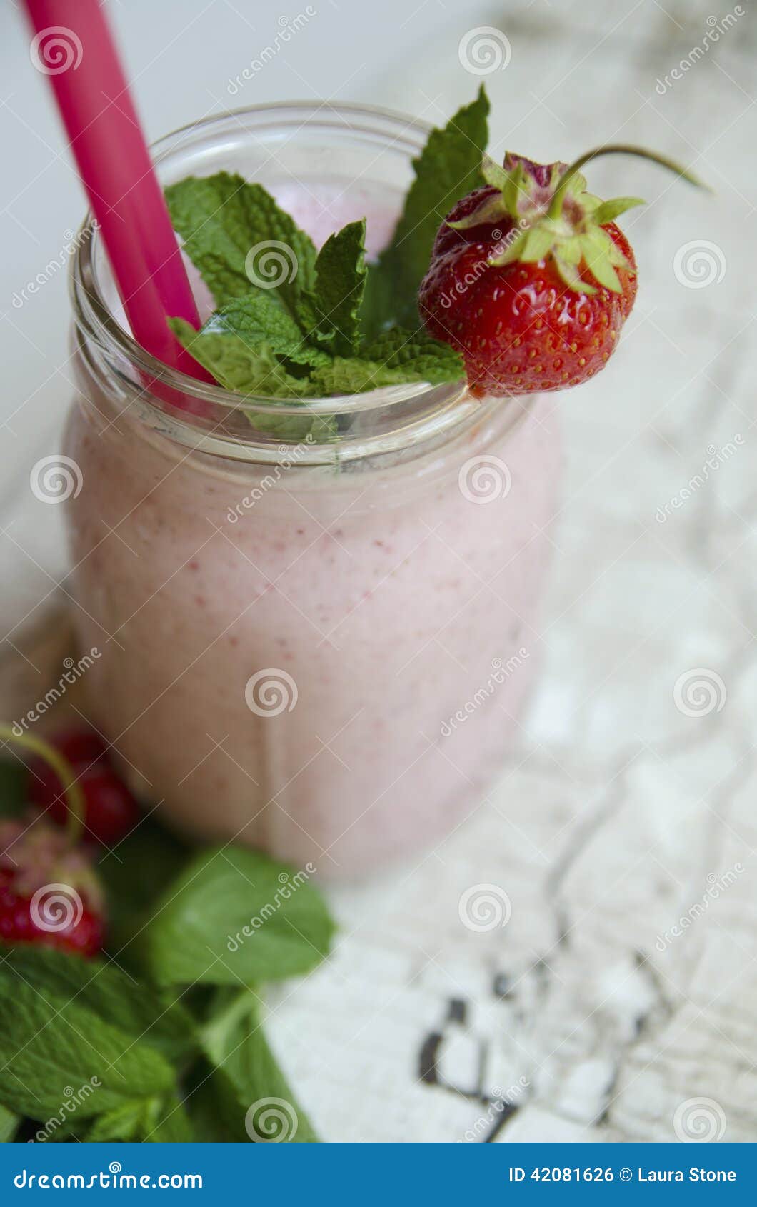 Smoothie клубники. A strawberry smoothie made with fresh fruit and yogurt, garnished with mint leaves and served in a canning jar.