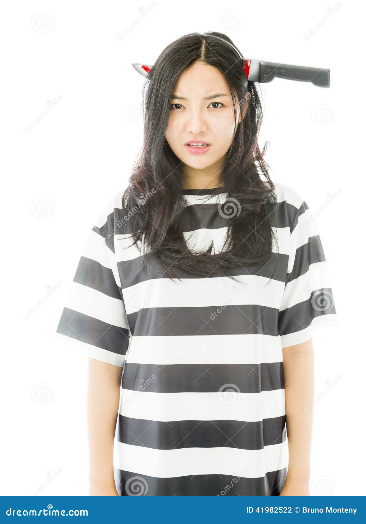 Smutna Azjatycka młoda kobieta jest ubranym nóż kształtującego włosianego zespołu w więźniach munduruje. Młoda atrakcyjna Azjatycka kobieta w jej 20's strzelał w studiu odizolowywającym na białym tle