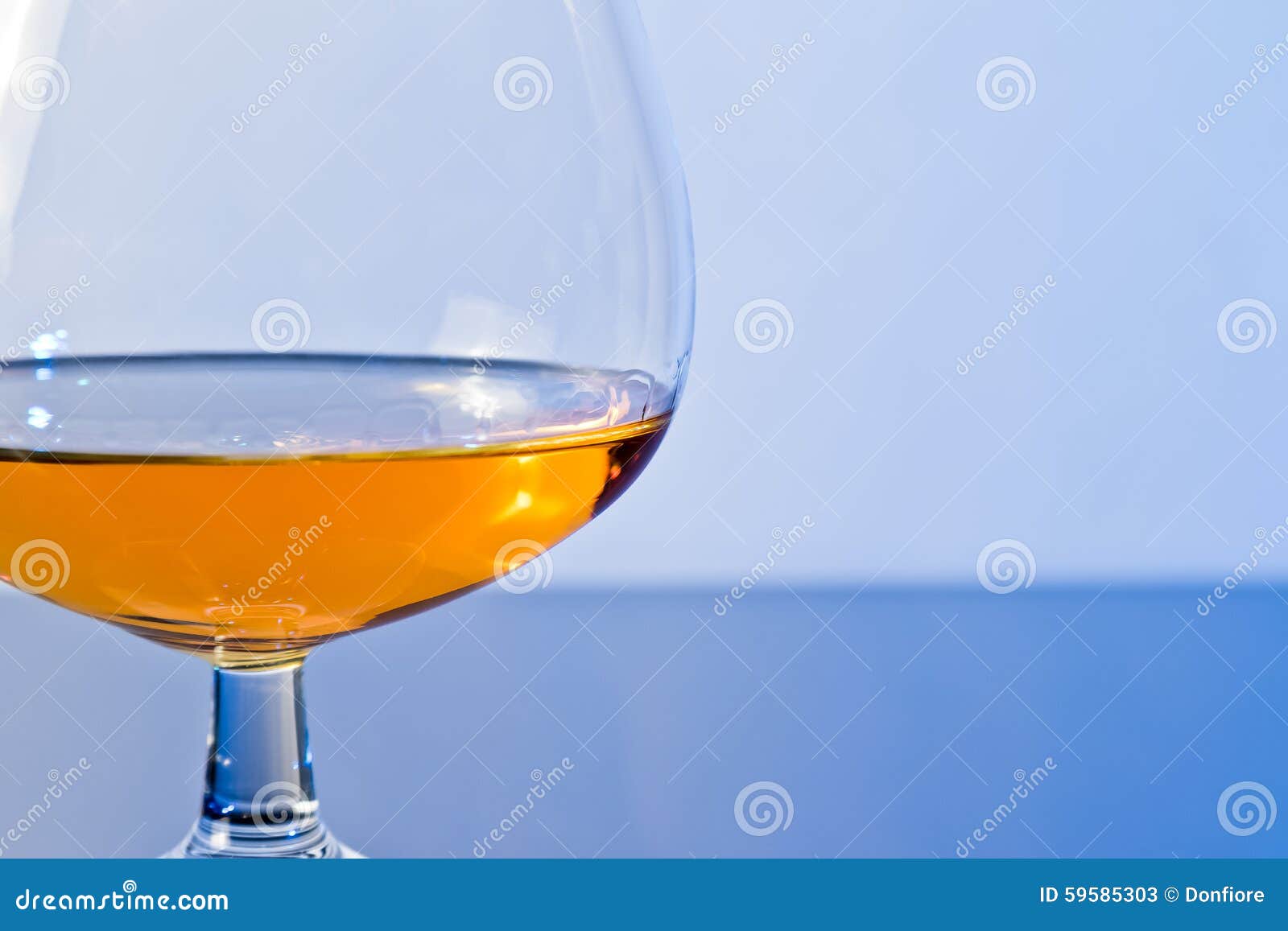 Snifter Of Brandy In Elegant Typical Cognac Glass On Blue Light