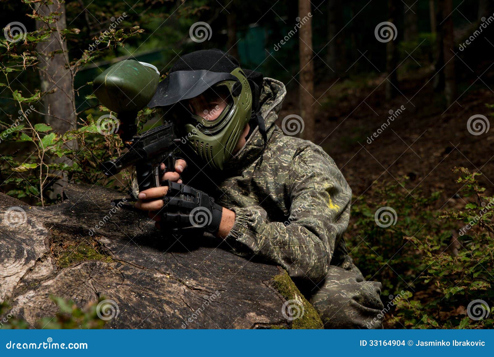 Sniper Aiming Gun. Paintball sport player in protective uniform and mask aiming and shooting with gun outdoors