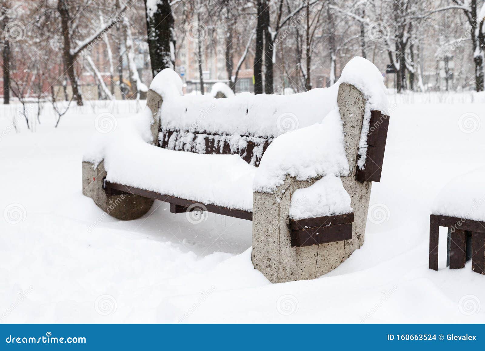 Snow Covered Bench Among Snowbanks In City Park Stock Photo